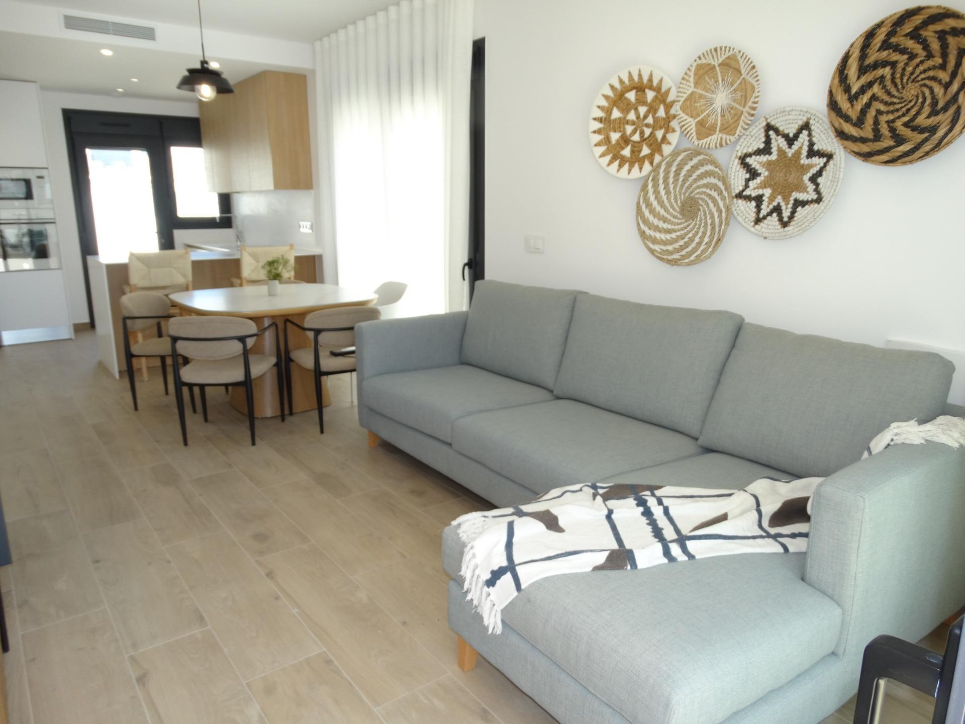 Modern-New-Build-Bungalows-for-Sale-in-Pilar-de-la-Horadada-7 Bright modern living room with elegant sofa and dining area in new build bungalows for sale in Pilar de la Horadada