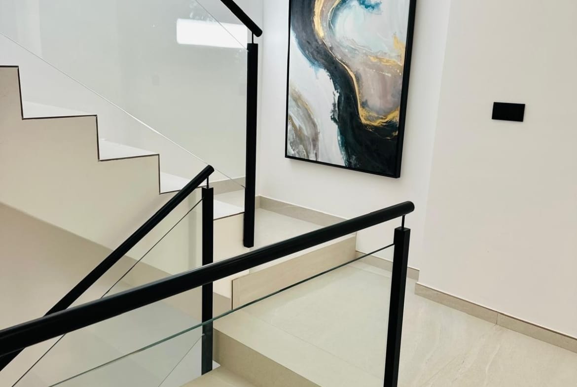 Bright modern staircase with sleek glass and black railings in a new build villa in San Pedro del Pinatar, Costa Cálida.