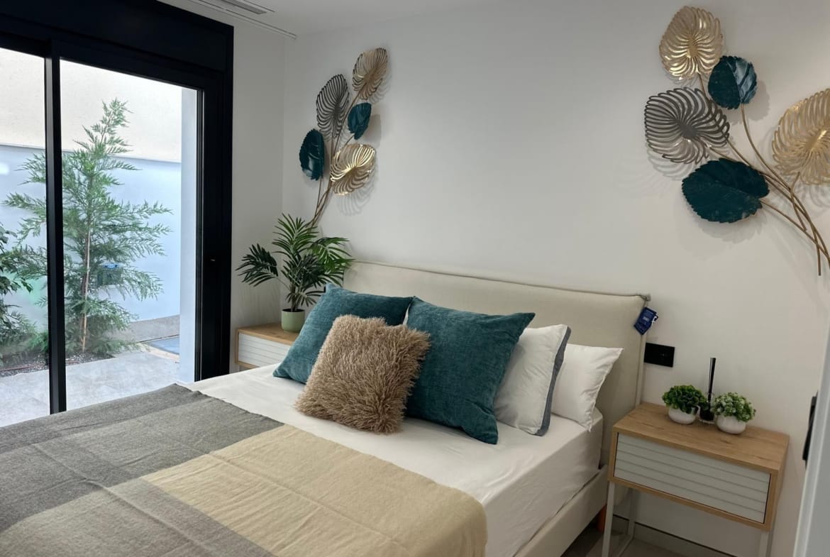 Bright, elegant bedroom with plush cushions and decorative wall art in key-ready new build villa, San Pedro del Pinatar, Costa Cálida.