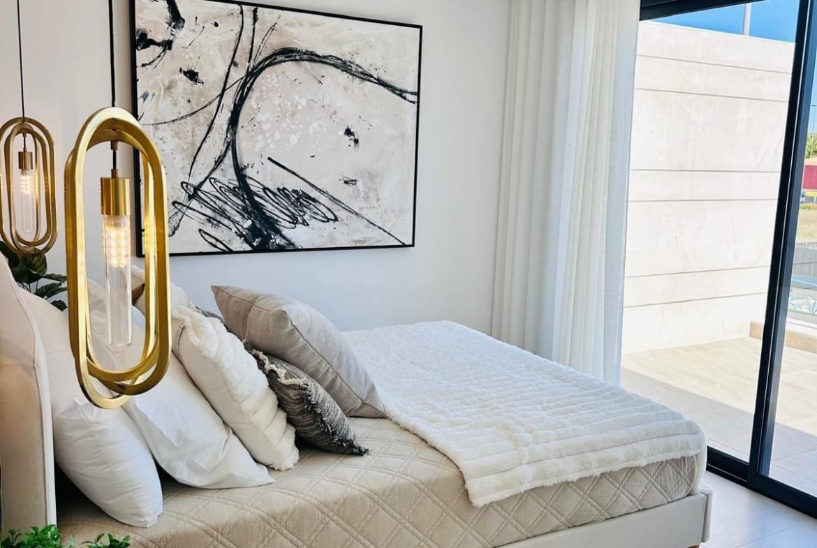Bright, elegant bedroom with modern gold pendant lights and balcony in key-ready villa in San Pedro del Pinatar, Costa Cálida.