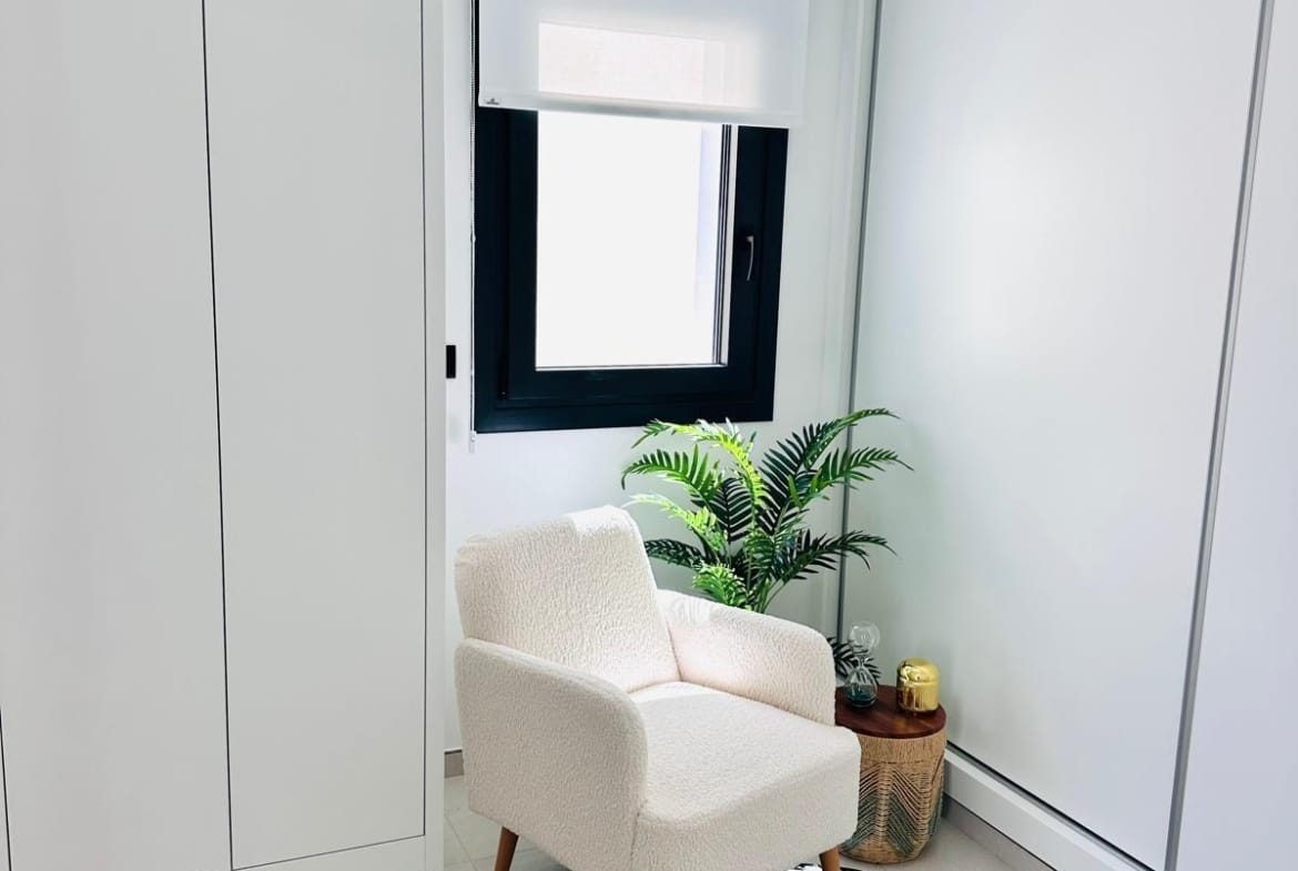 Bright minimalist reading nook with plush armchair and lush plant in key-ready new build villa in San Pedro del Pinatar, Costa Cálida