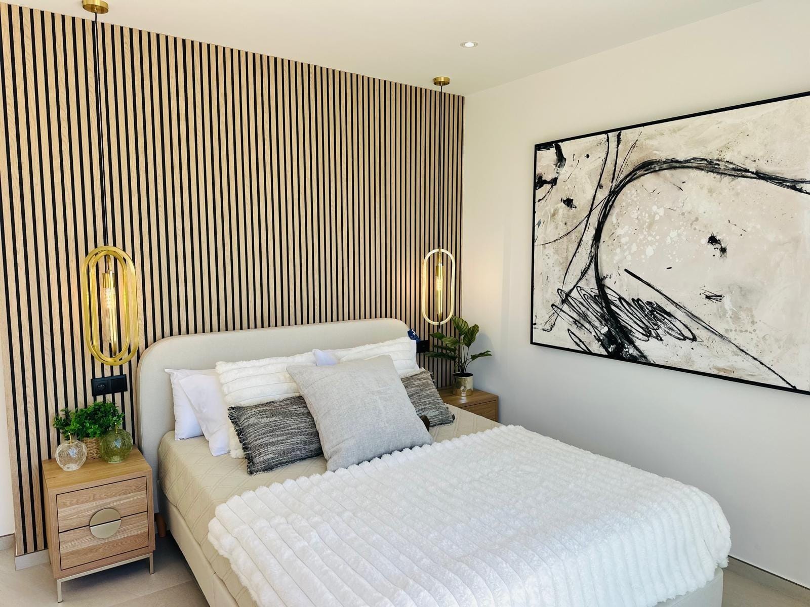 Modern-New-Build-Villas-for-Sale-in-San-Pedro-del-Pinatar-–-Close-to-Beach-and-Town-Centre-17 Bright modern bedroom with elegant wood paneling, gold pendant lights, and abstract art in a luxury villa in San Pedro del Pinatar.