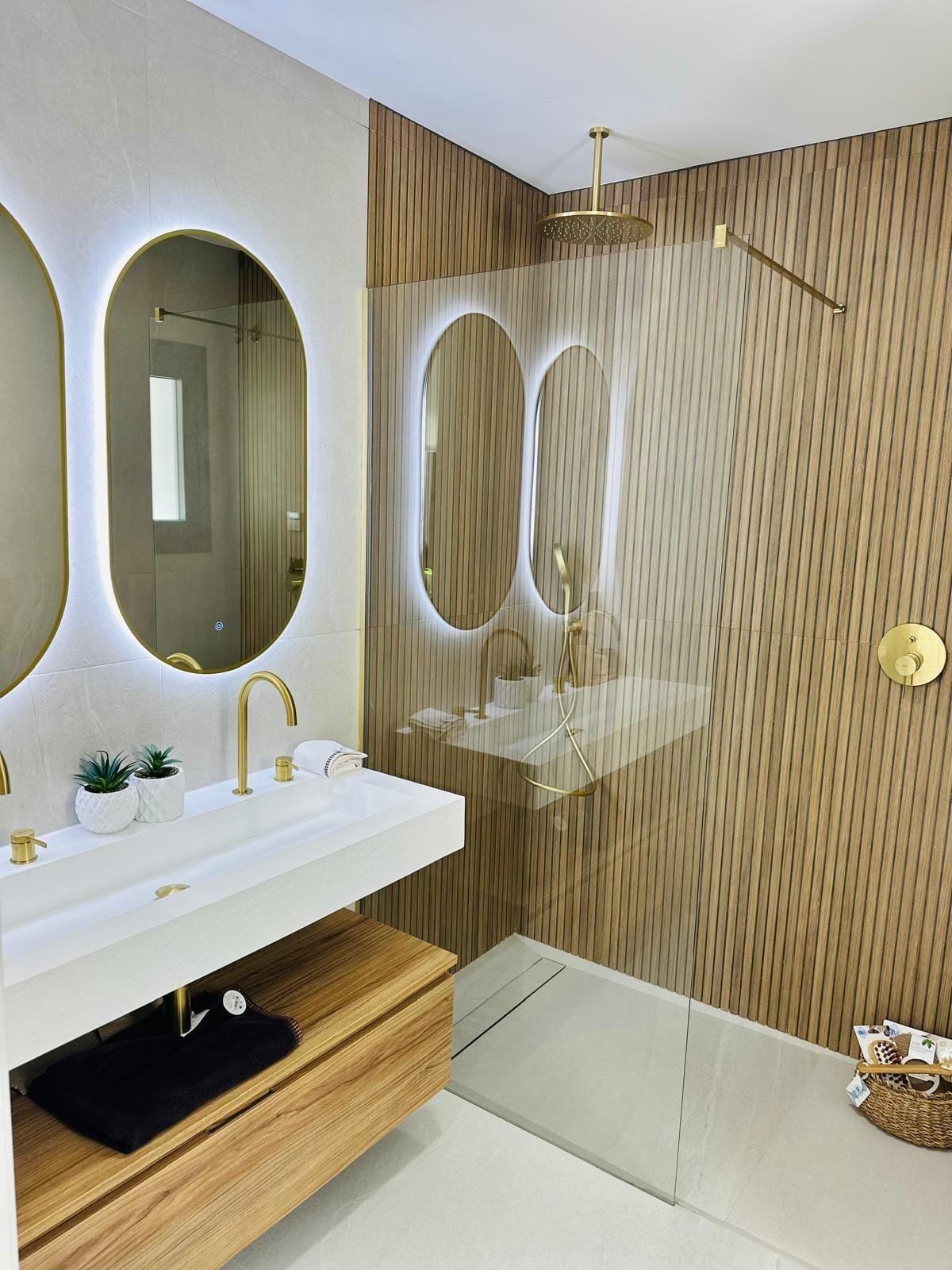 Modern-New-Build-Villas-for-Sale-in-San-Pedro-del-Pinatar-–-Close-to-Beach-and-Town-Centre-18 Modern luxury bathroom with illuminated oval mirrors, gold fixtures, and sleek wooden accents in San Pedro del Pinatar villa.