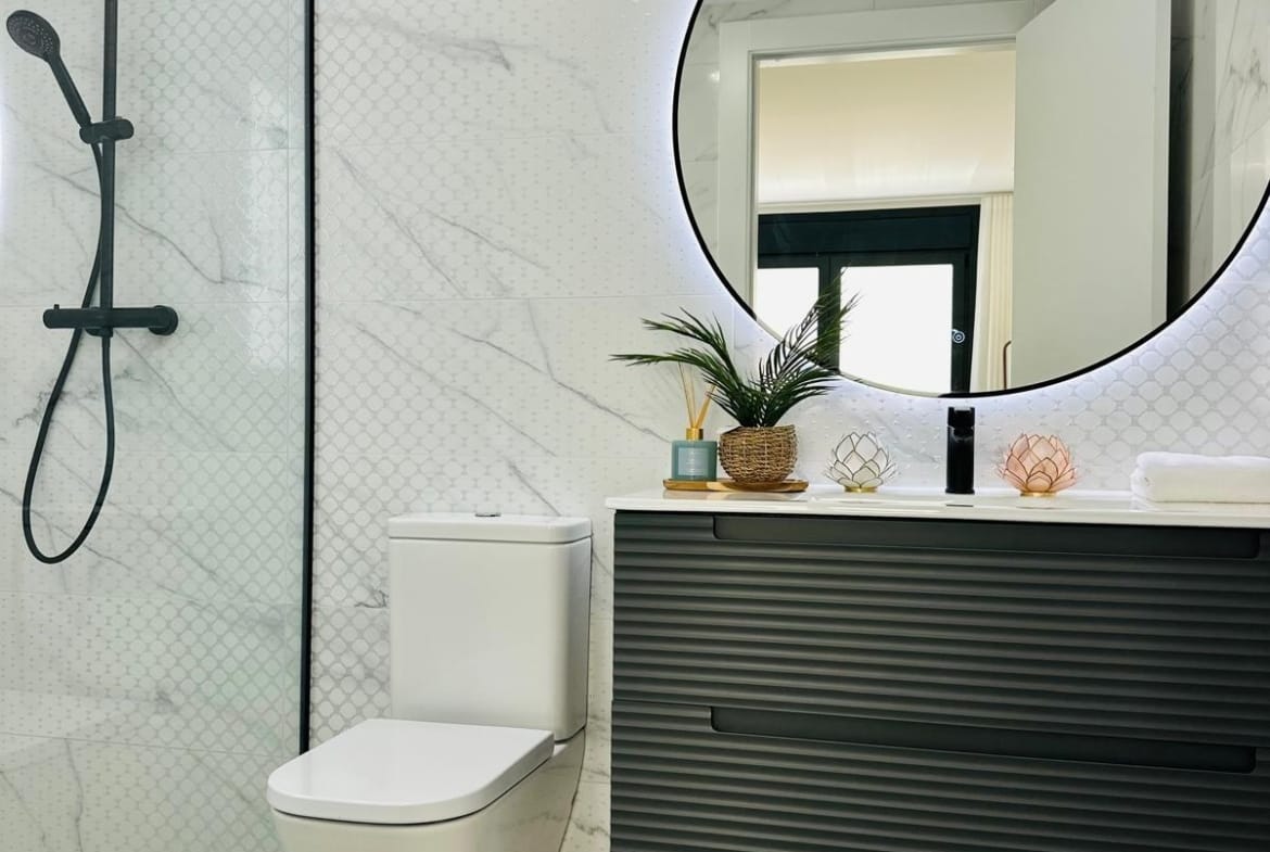 Modern sleek bathroom with floating vanity, backlit round mirror, and marble tiles in luxury villa San Pedro del Pinatar Costa Cálida