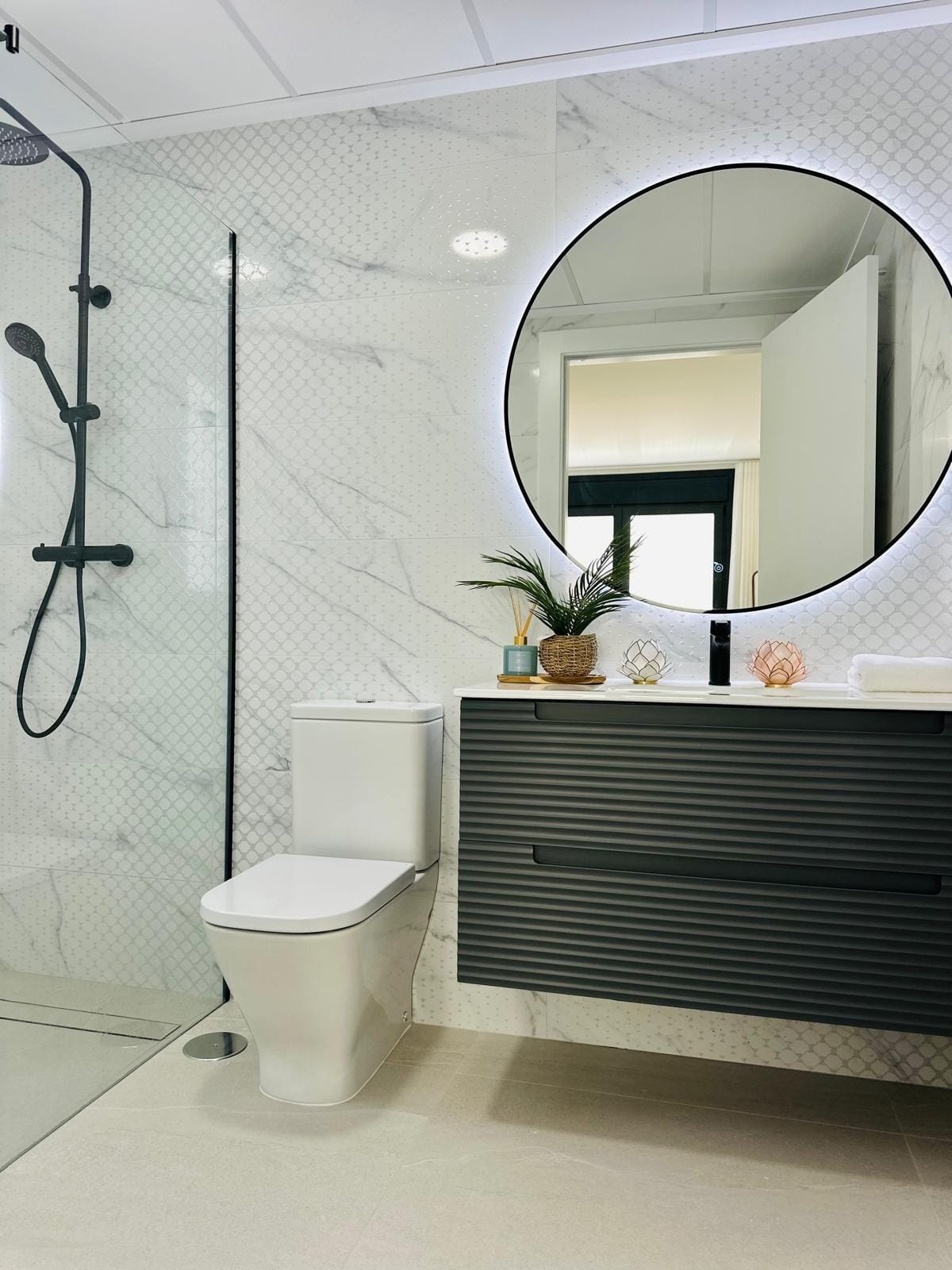 Modern-New-Build-Villas-for-Sale-in-San-Pedro-del-Pinatar-–-Close-to-Beach-and-Town-Centre-19 Modern sleek bathroom with floating vanity, backlit round mirror, and marble tiles in luxury villa San Pedro del Pinatar Costa Cálida