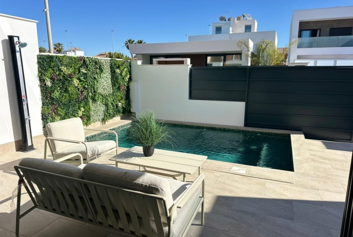 Sun-drenched terrace with modern seating and a private pool beside a lush vertical garden at a new build villa in San Pedro del Pinatar.