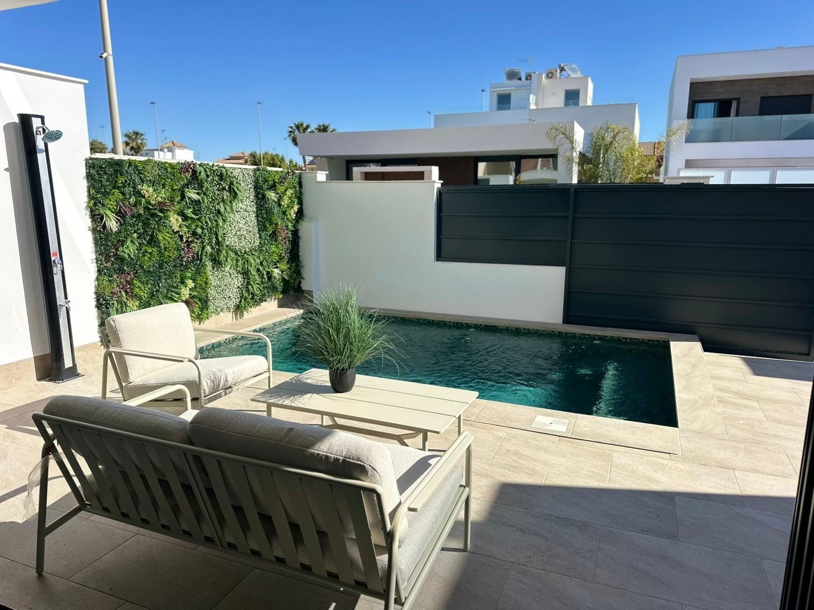Modern-New-Build-Villas-for-Sale-in-San-Pedro-del-Pinatar-–-Close-to-Beach-and-Town-Centre-2 Sun-drenched terrace with modern seating and a private pool beside a lush vertical garden at a new build villa in San Pedro del Pinatar.