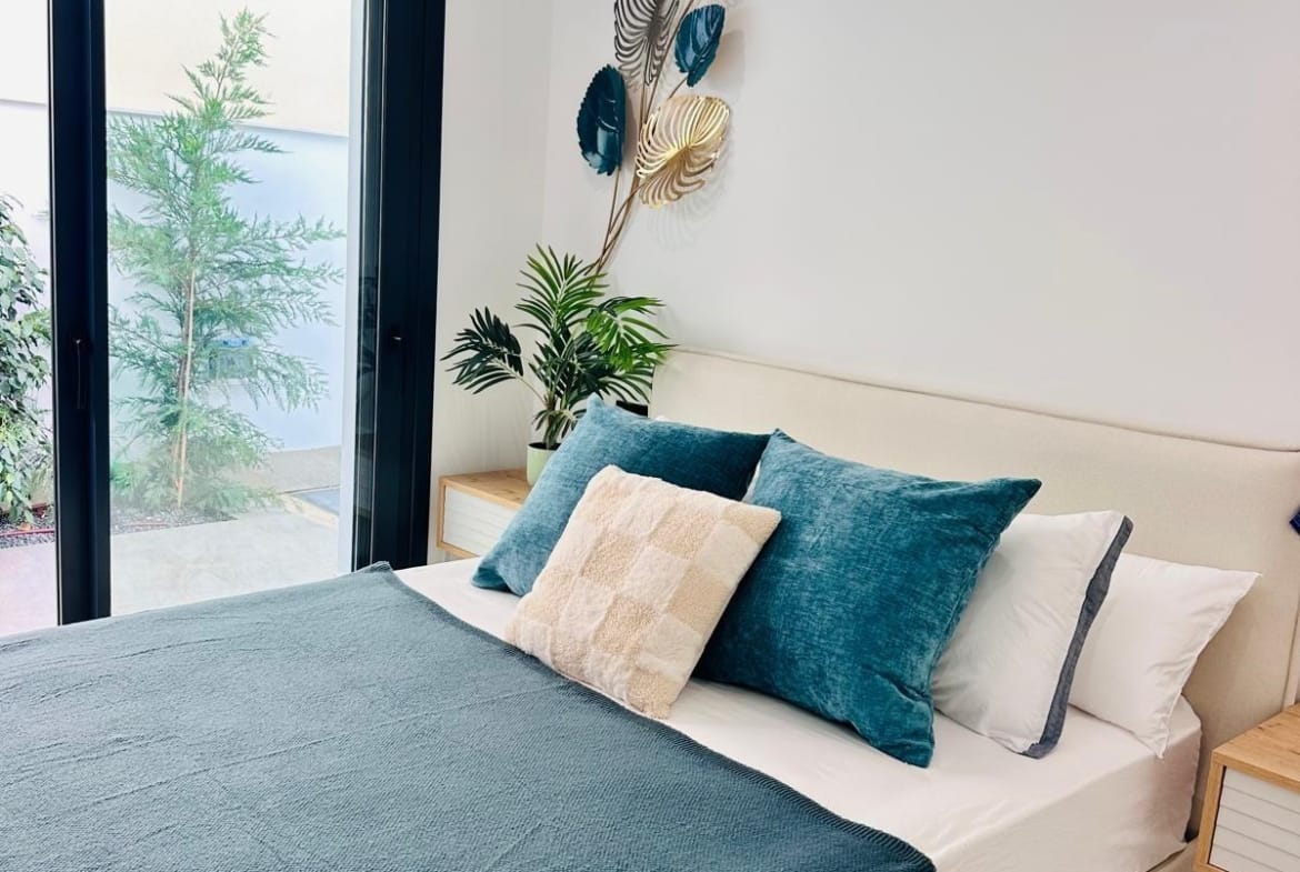 Bright modern bedroom with plush teal bedding and sliding doors opening to a private terrace in San Pedro del Pinatar villa.
