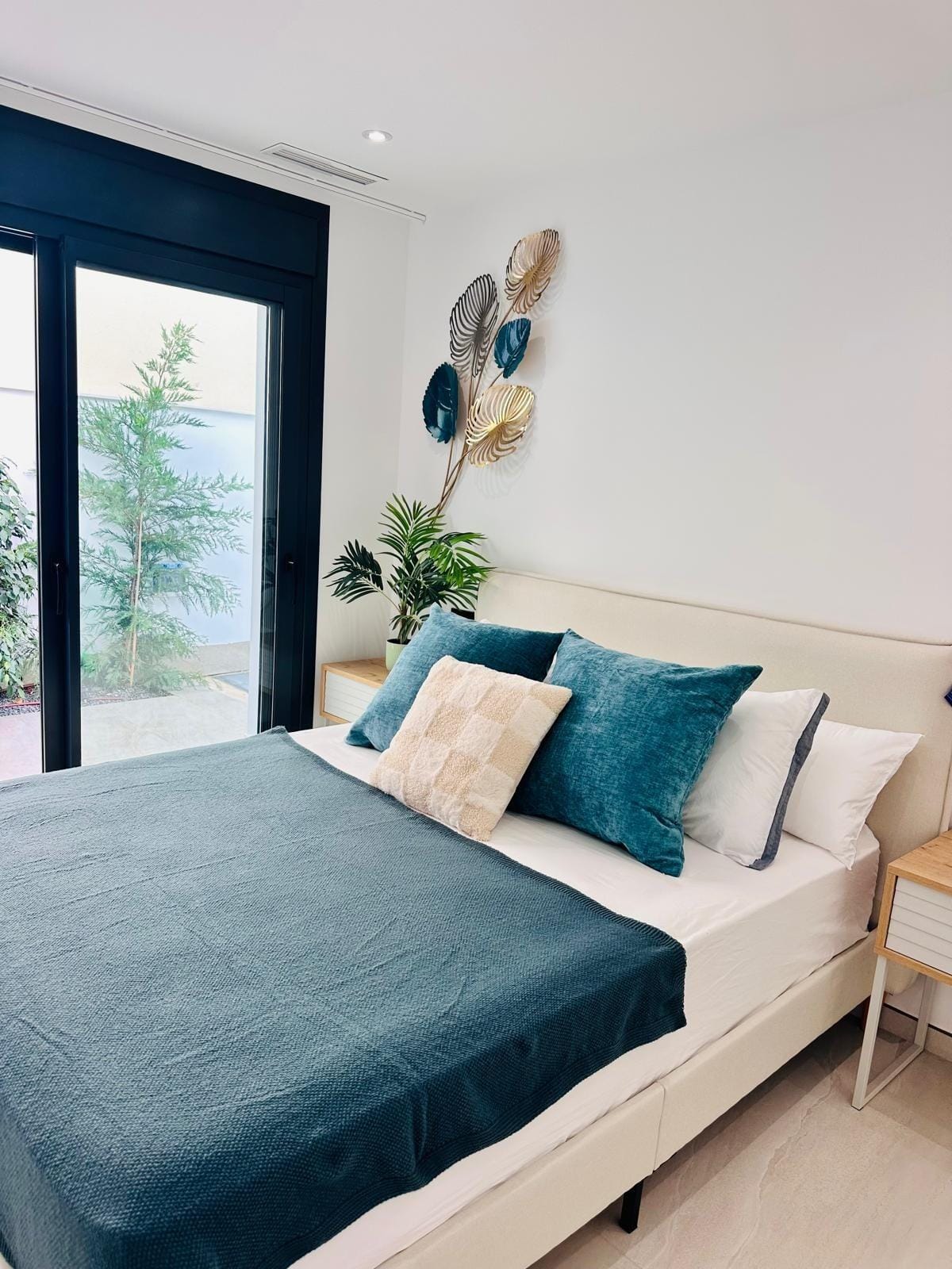 Modern-New-Build-Villas-for-Sale-in-San-Pedro-del-Pinatar-–-Close-to-Beach-and-Town-Centre-23 Bright modern bedroom with plush teal bedding and sliding doors opening to a private terrace in San Pedro del Pinatar villa.