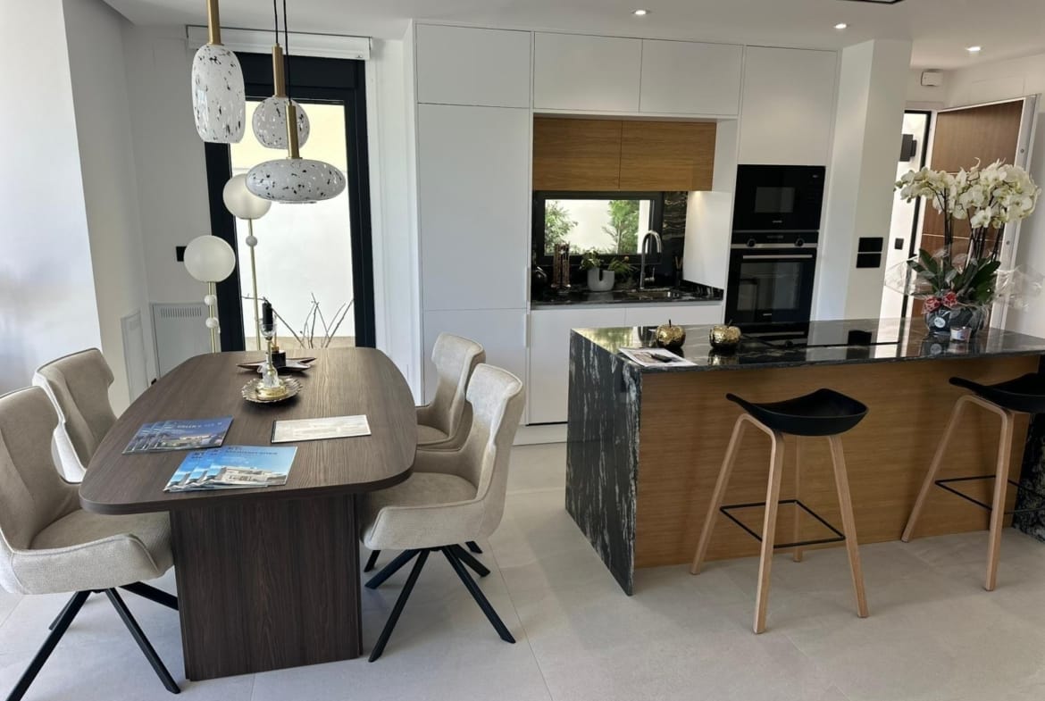 Modern open-plan kitchen and dining area with sleek marble island and elegant wood details in San Pedro del Pinatar villa.