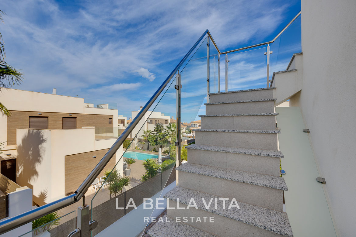 Modern villa with private pool, solarium and basement near La Mata beach, Torrevieja-13 Elegant staircase with glass railing overlooking the landscaped terrace and private pool of a modern 4-bedroom villa in Torreblanca, Torrevieja