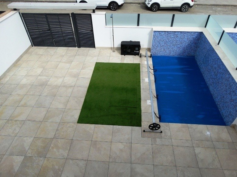 Sleek modern patio with private blue-tiled pool and minimalist lawn area at 3-bedroom villa in Pilar de la Horadada