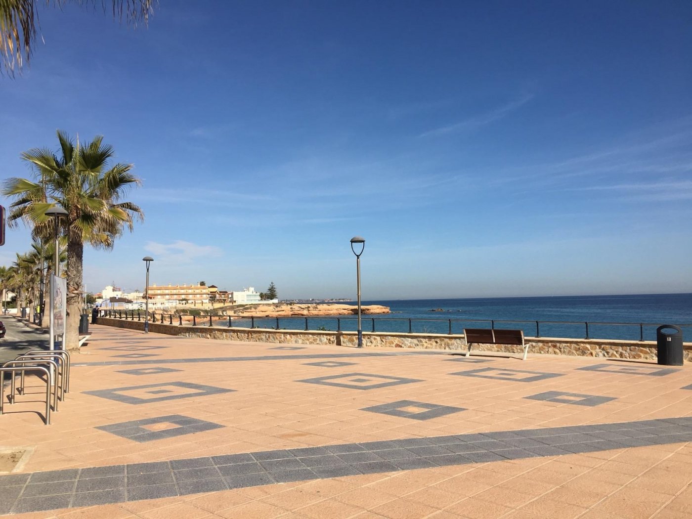 Sun-drenched waterfront promenade with palm trees and panoramic sea views near luxury villas in Pilar de la Horadada