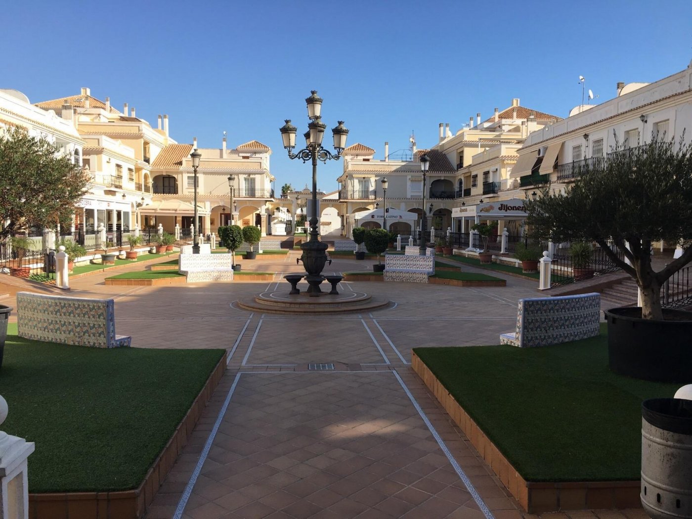 Bright, spacious plaza with elegant street lamps surrounded by modern semi-detached villas in Pilar de la Horadada