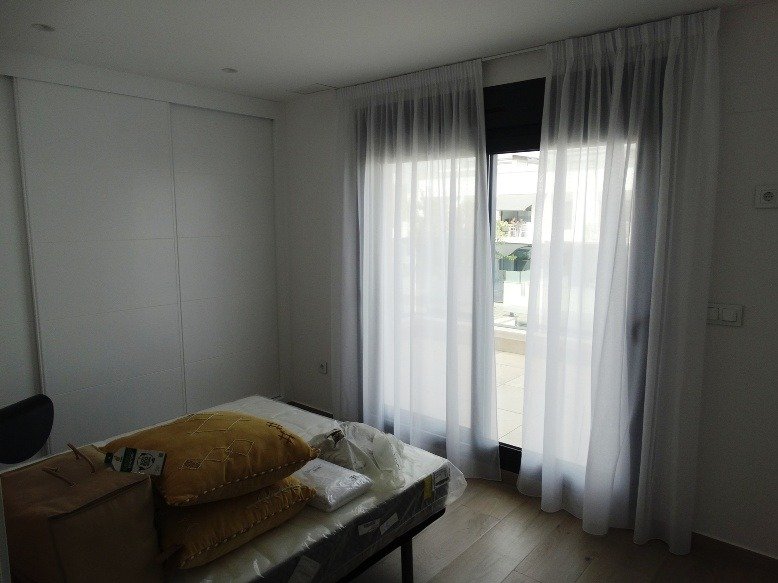 Bright modern bedroom with sheer curtains and wooden floors in a new 3-bedroom semi-detached villa in Pilar de la Horadada.