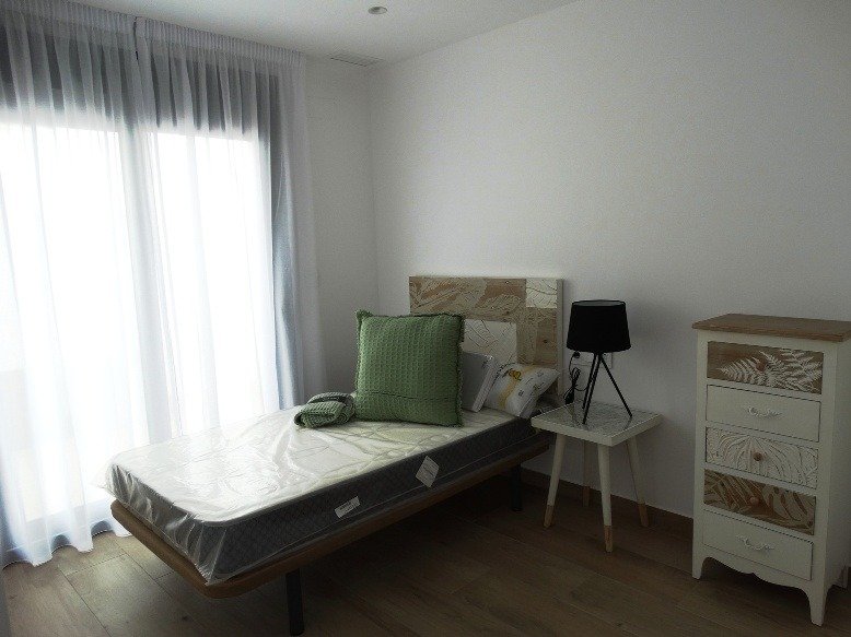 Bright, minimalist bedroom with natural light and elegant wooden flooring in modern 3-bedroom villa in Pilar de la Horadada