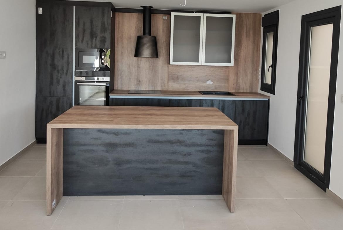 Modern open-plan kitchen with sleek cabinetry and wood accents in a new 3-bedroom apartment in Torre-Pacheco, Murcia