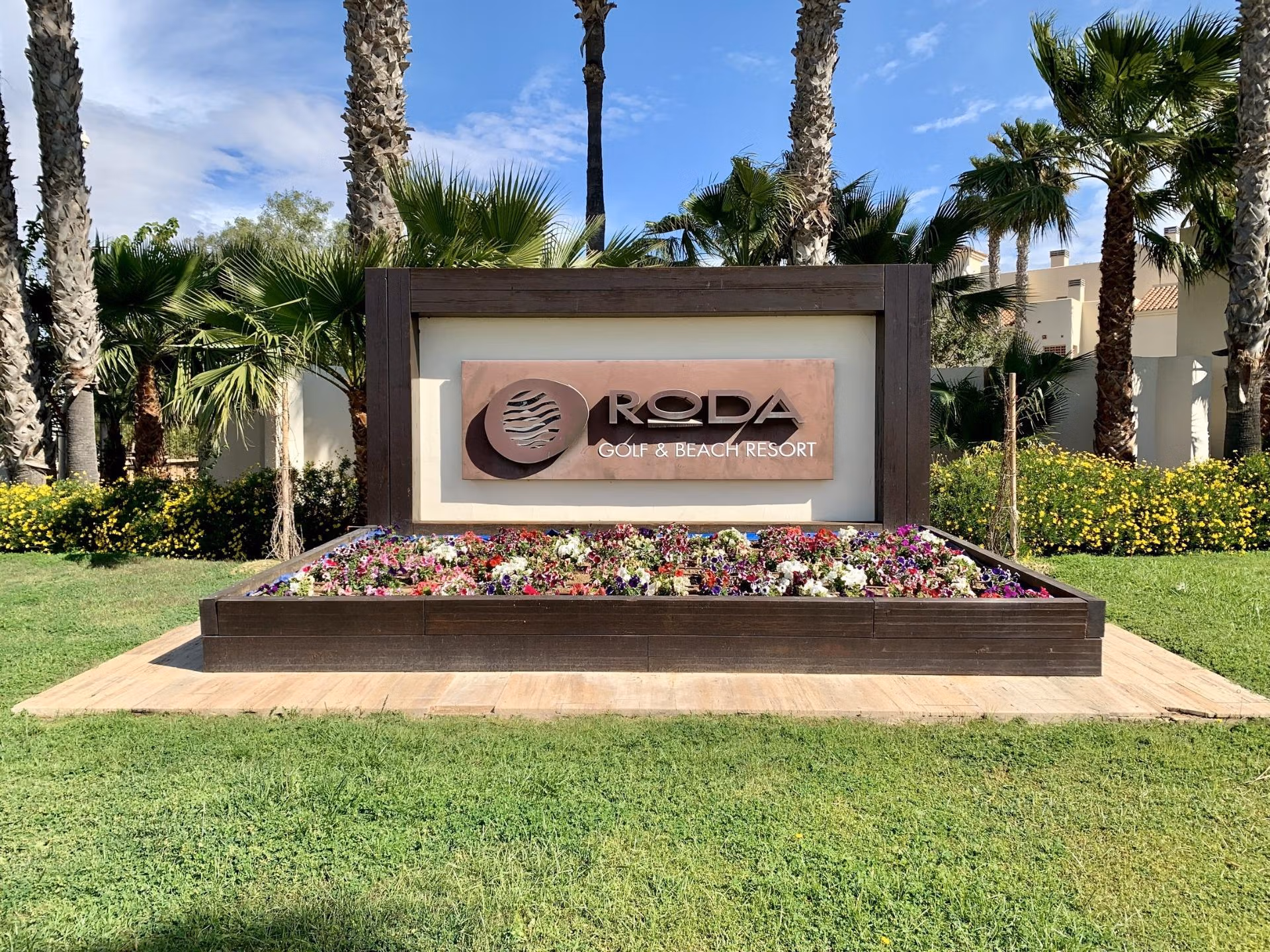 Lush landscaped entrance with tropical palms and vibrant flowers at Roda Golf & Beach Resort near San Javier, ideal for luxury living