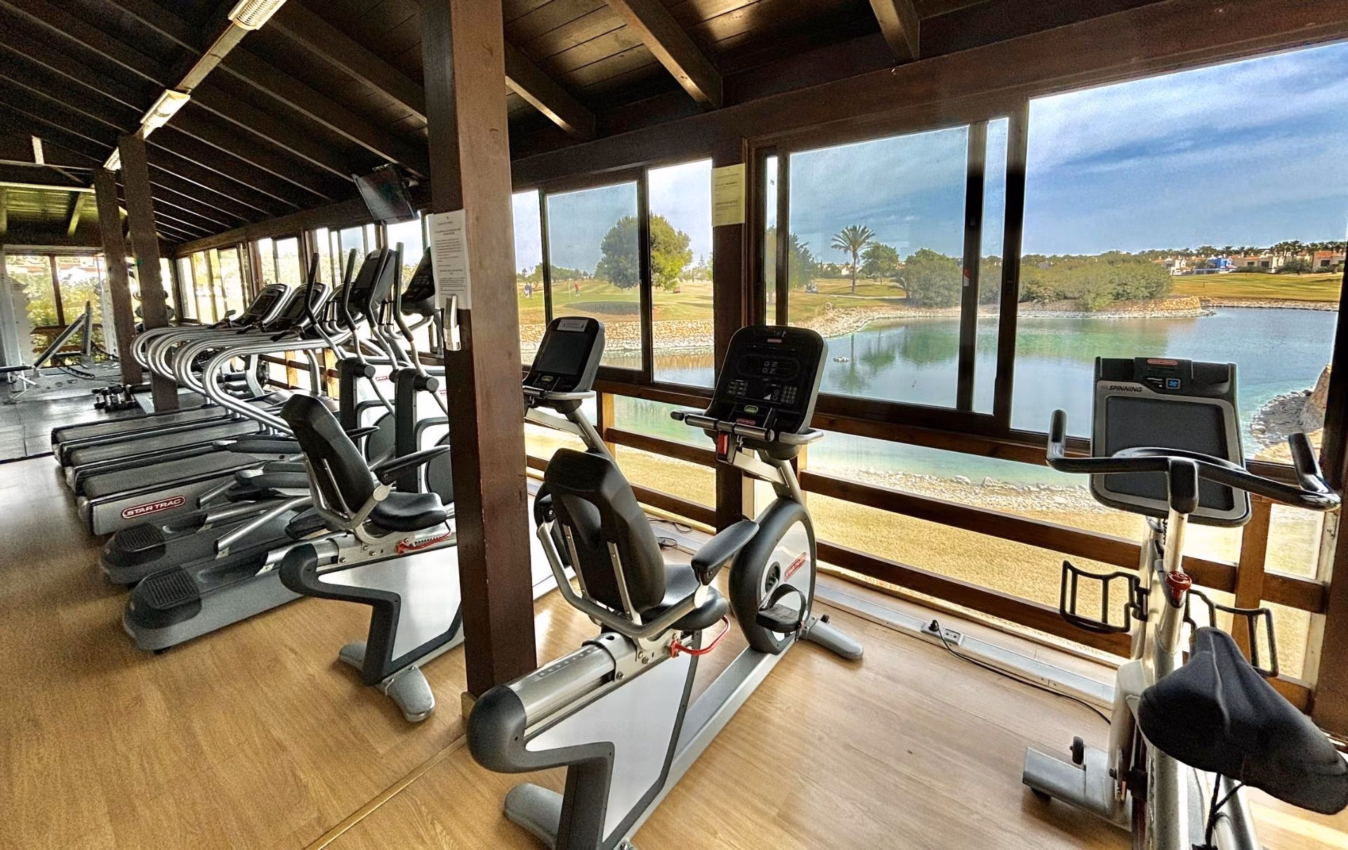 Bright, spacious gym with modern cardio equipment overlooking a serene lake at Roda Golf, San Javier near the new 3-bedroom bungalow.