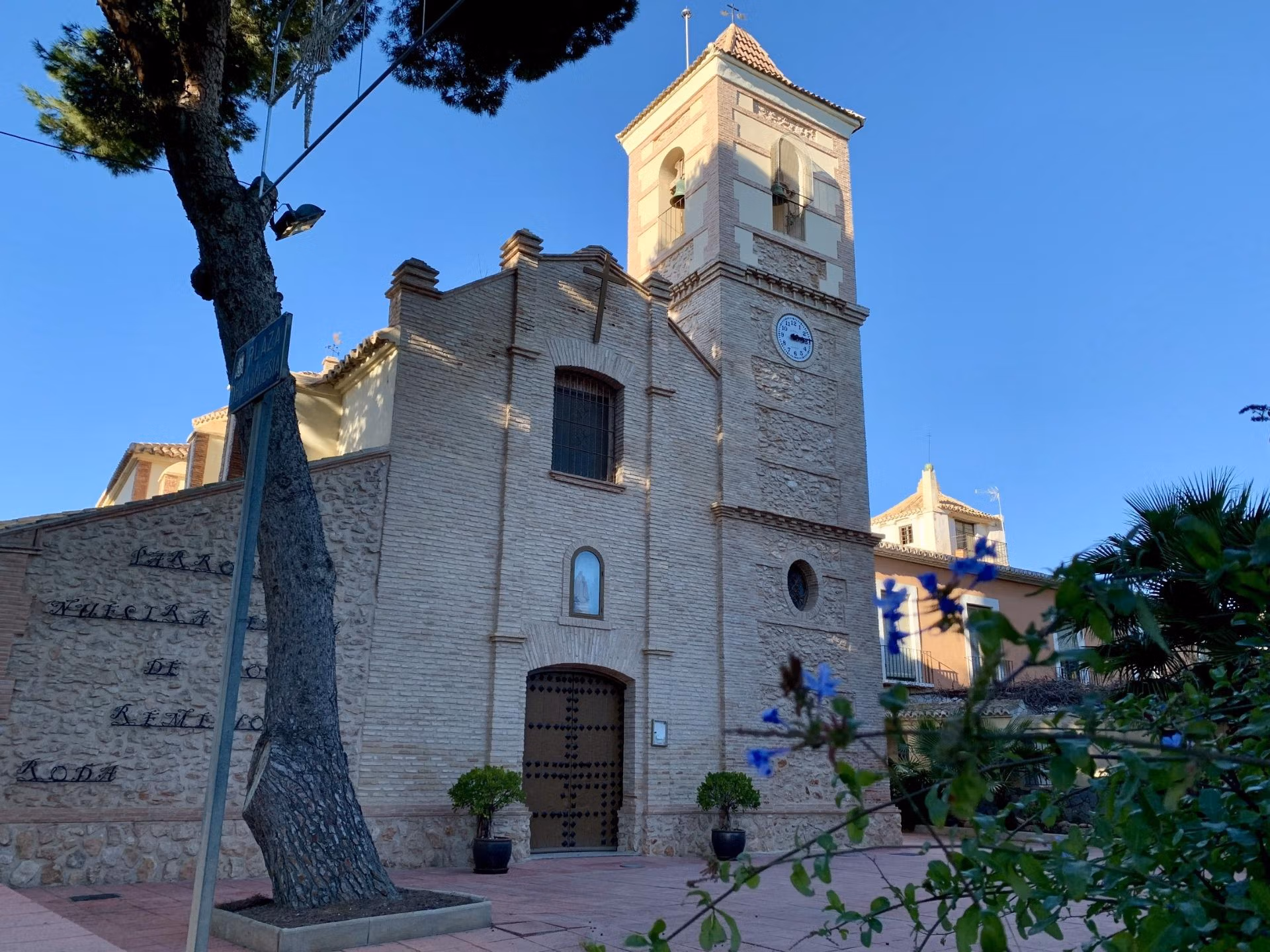Historic rustic church with bright stone façade and clock tower near Roda Golf, San Javier, surrounded by greenery.