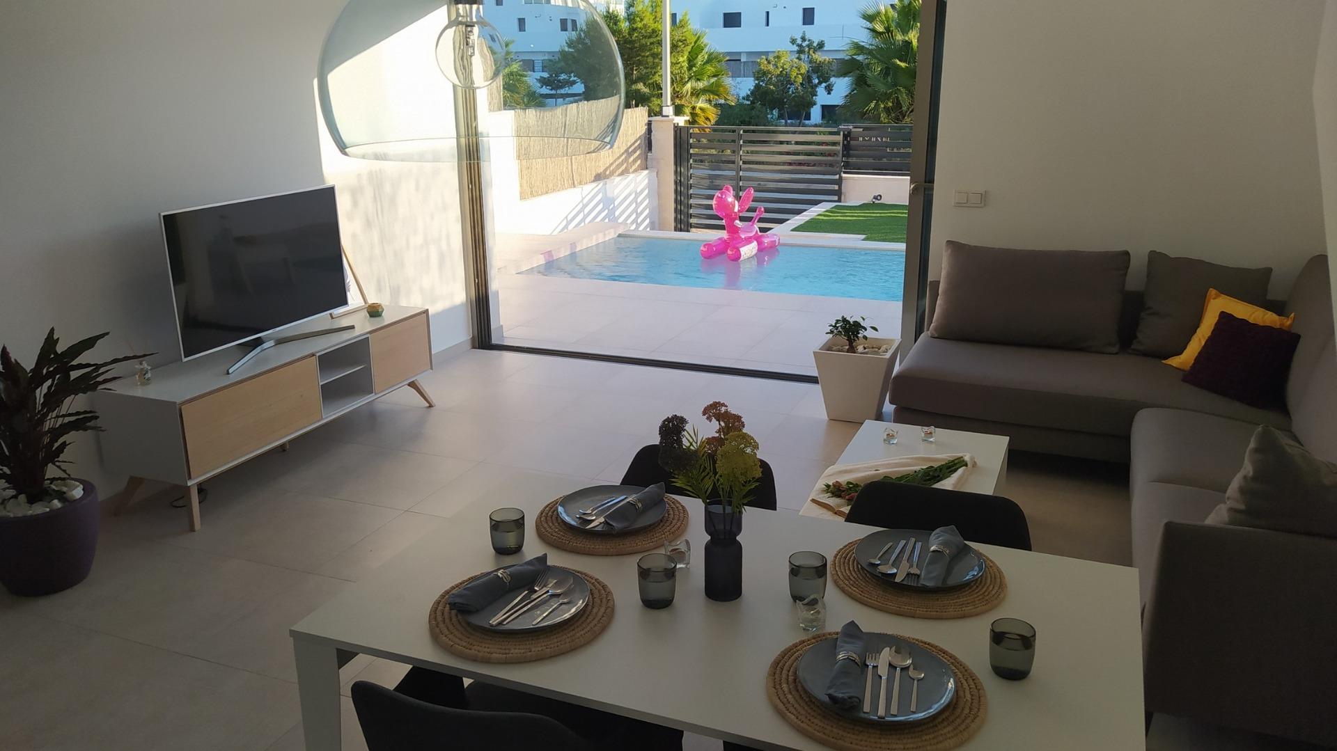 Bright modern open-plan living and dining area with sleek furnishings overlooking a private pool in a 3-bedroom villa in Villamartin.