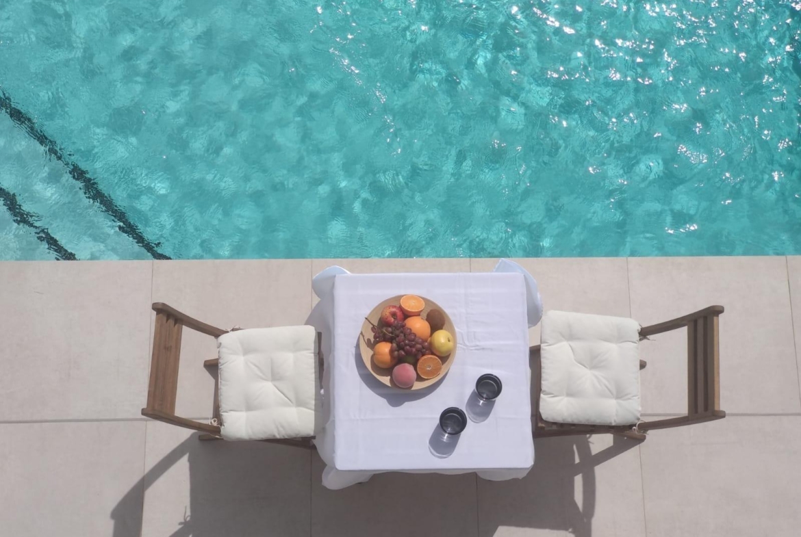 Sun-drenched private pool terrace with cushioned chairs and fruit platter at modern 3-bedroom villa in Villamartin, Orihuela Costa