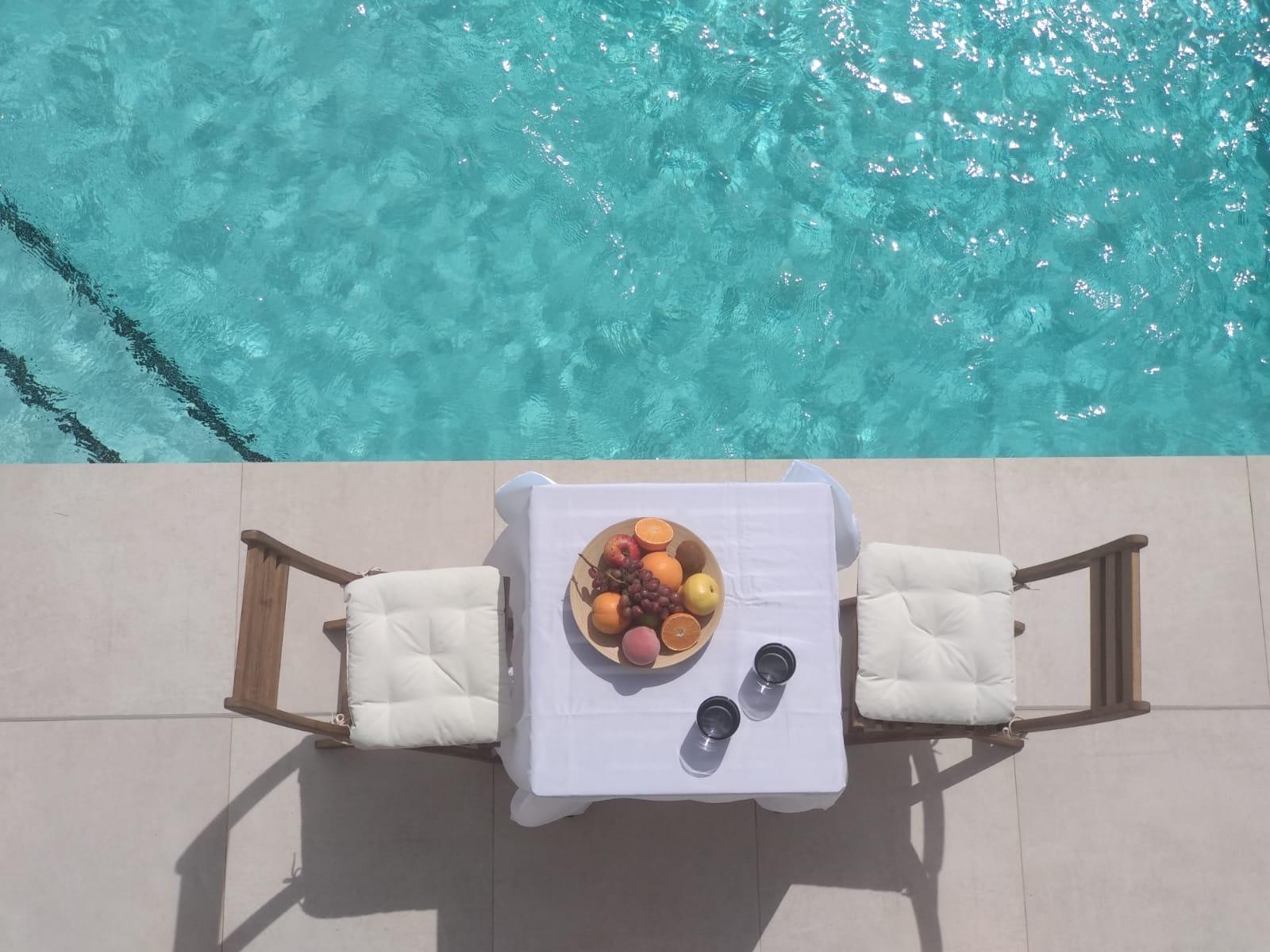Sun-drenched private pool terrace with cushioned chairs and fruit platter at modern 3-bedroom villa in Villamartin, Orihuela Costa