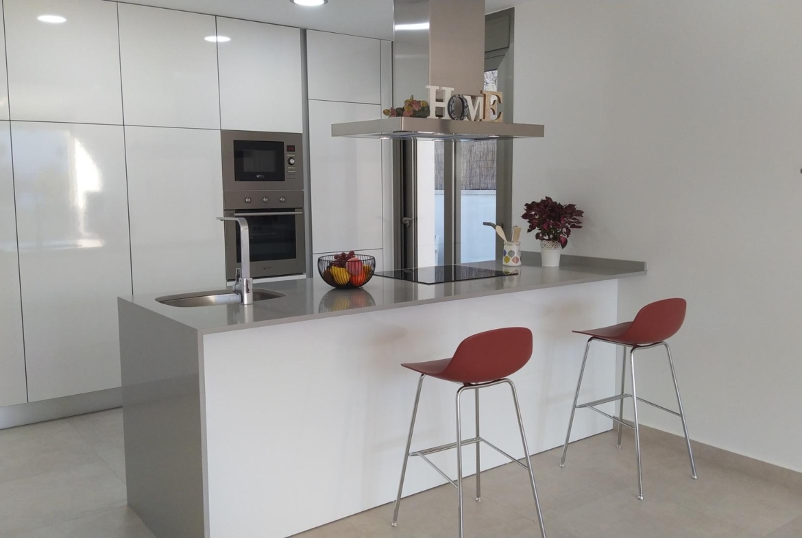 Bright modern kitchen with sleek white cabinetry and breakfast bar in luxury 3-bedroom villa, Villamartin, Orihuela Costa.