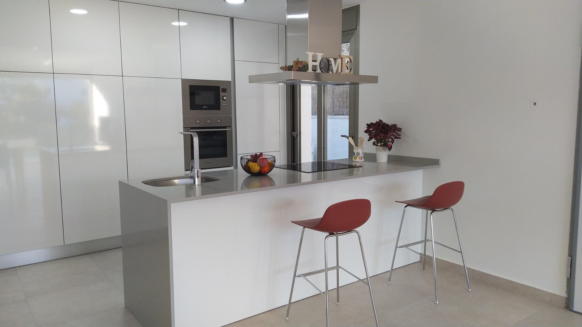 Bright modern kitchen with sleek white cabinetry and breakfast bar in luxury 3-bedroom villa, Villamartin, Orihuela Costa.