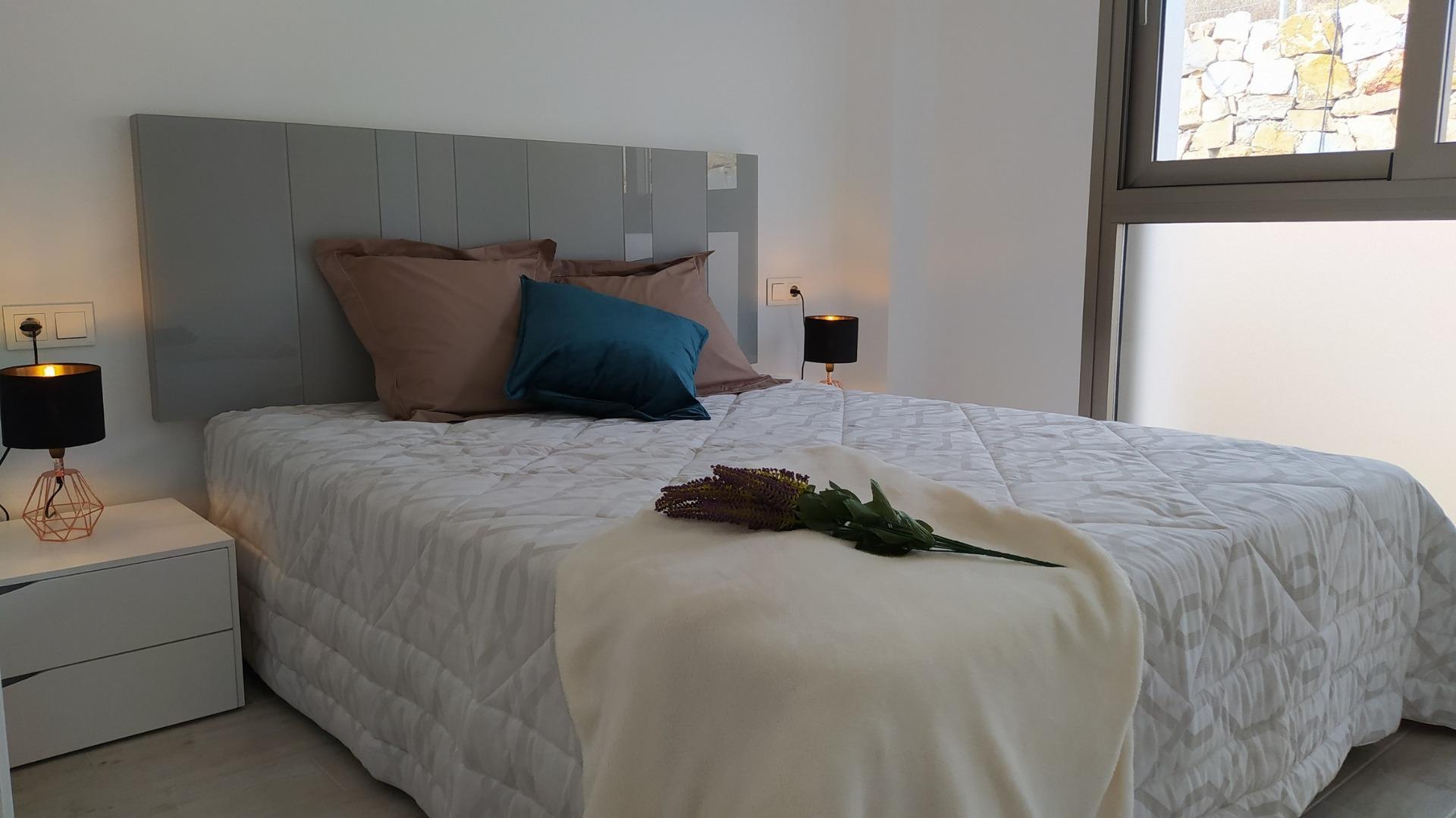 Bright modern bedroom with soft linens and bedside lamps in a new 3-bedroom villa in Villamartin, Orihuela Costa.