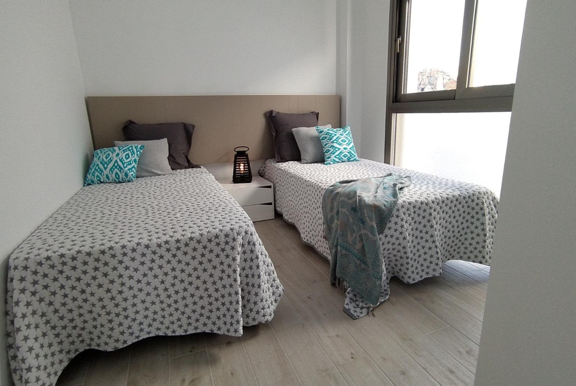 Bright modern twin bedroom with large window and minimalist decor in a 3-bedroom villa in Villamartin, Orihuela Costa.