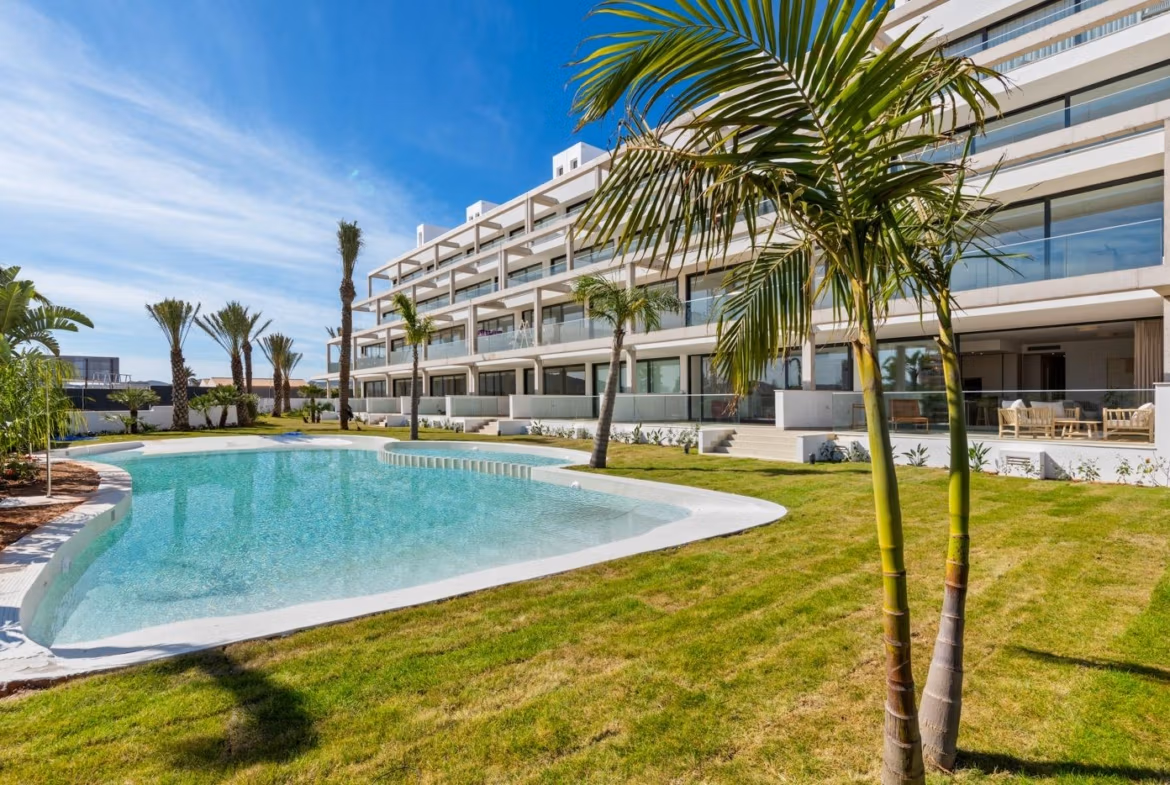 Modern luxury penthouse building with lush landscaping and a sparkling pool in sunny Mar de Cristal.
