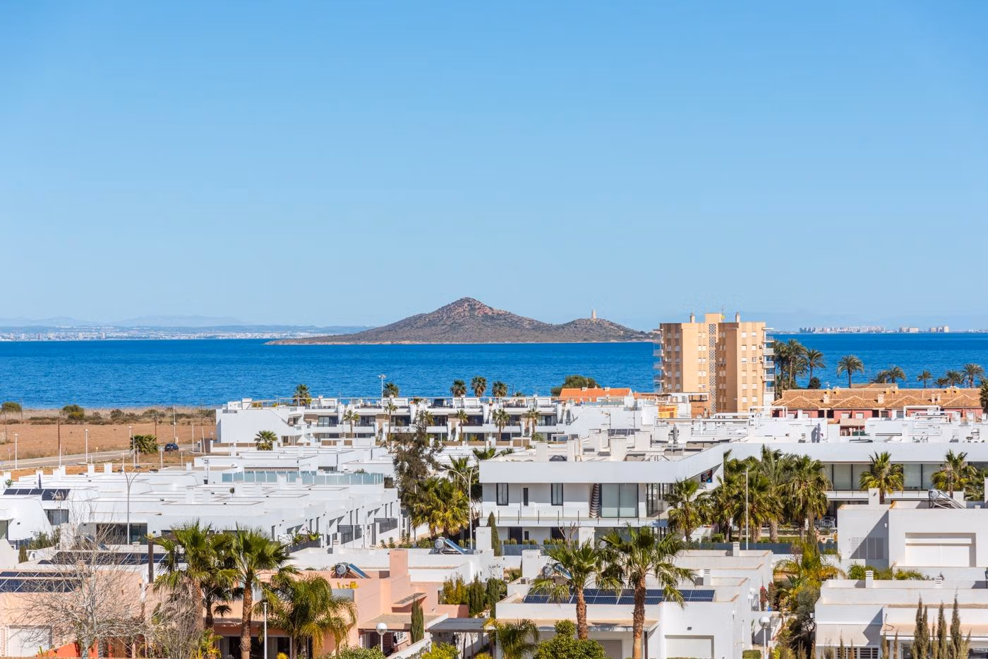 Panoramic sea view over white modern rooftops and lush palm trees from elevated 2-bedroom penthouse solarium in Mar de Cristal.