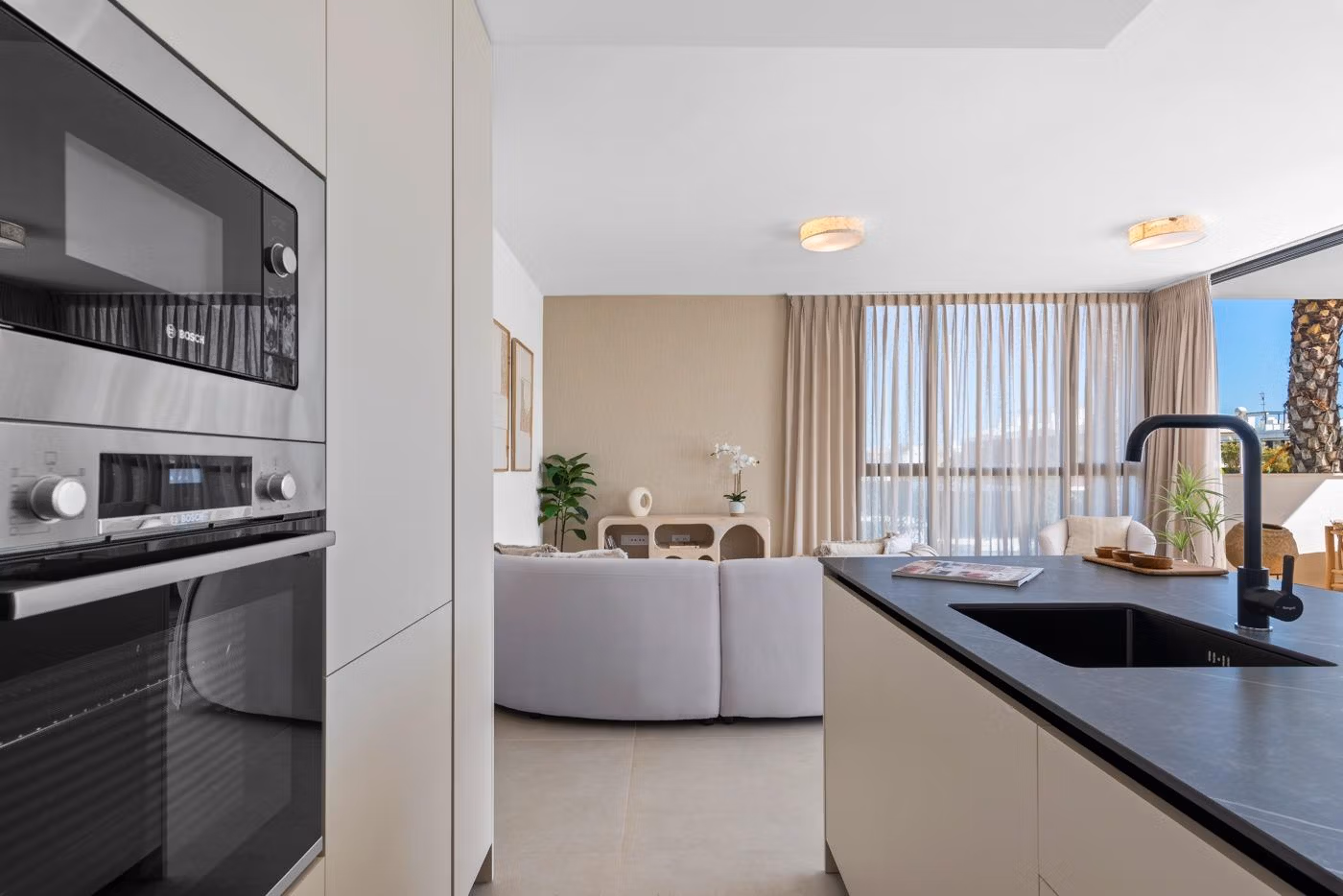 Bright modern kitchen and living area with sleek appliances and large window in elevated 2 bedroom penthouse in Mar de Cristal