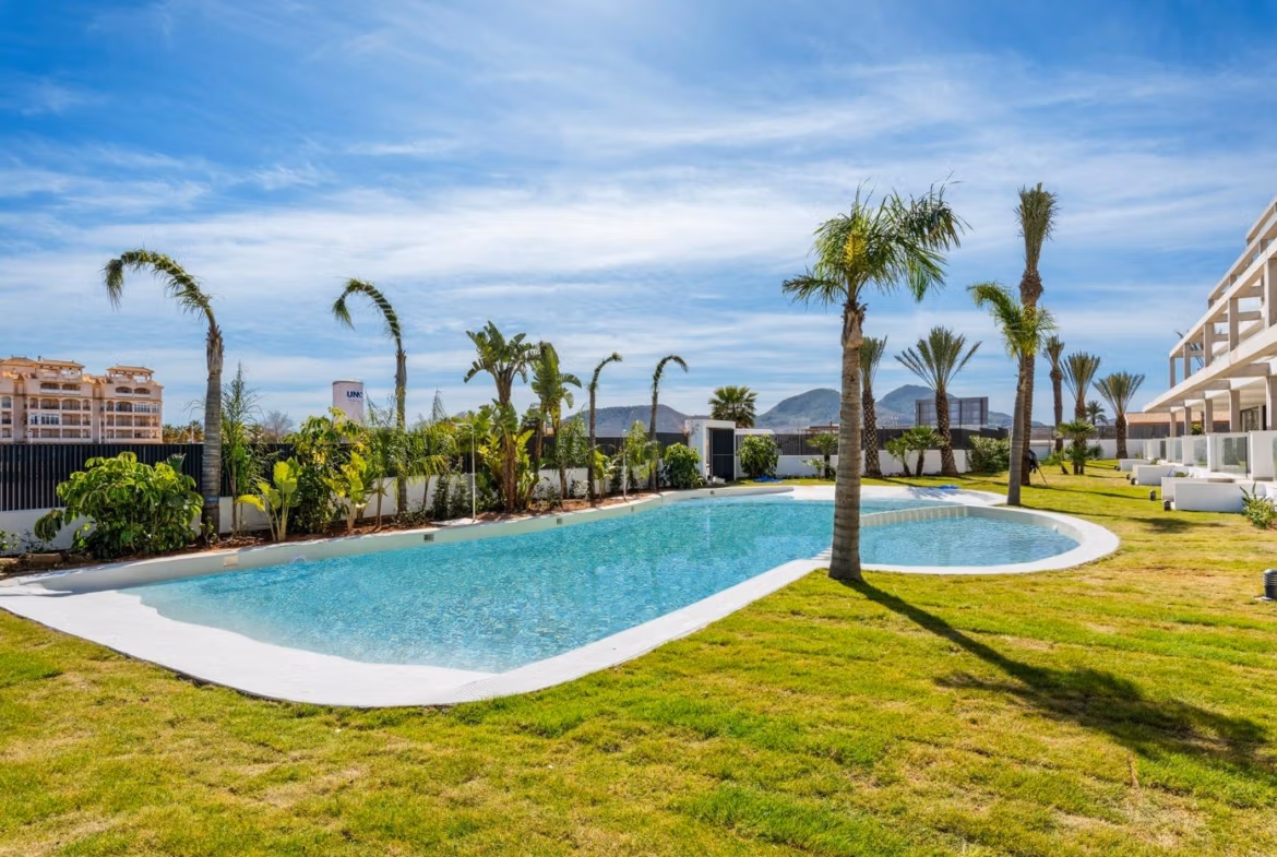 Stunning landscaped pool area with palm trees beside elevated new build penthouse in Mar de Cristal under clear blue sky
