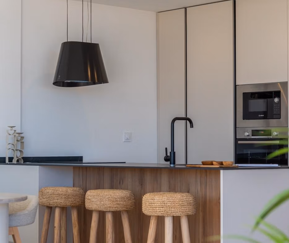 Modern kitchen with sleek black fixtures and natural wood stools in elevated 2-bedroom penthouse in Mar de Cristal.
