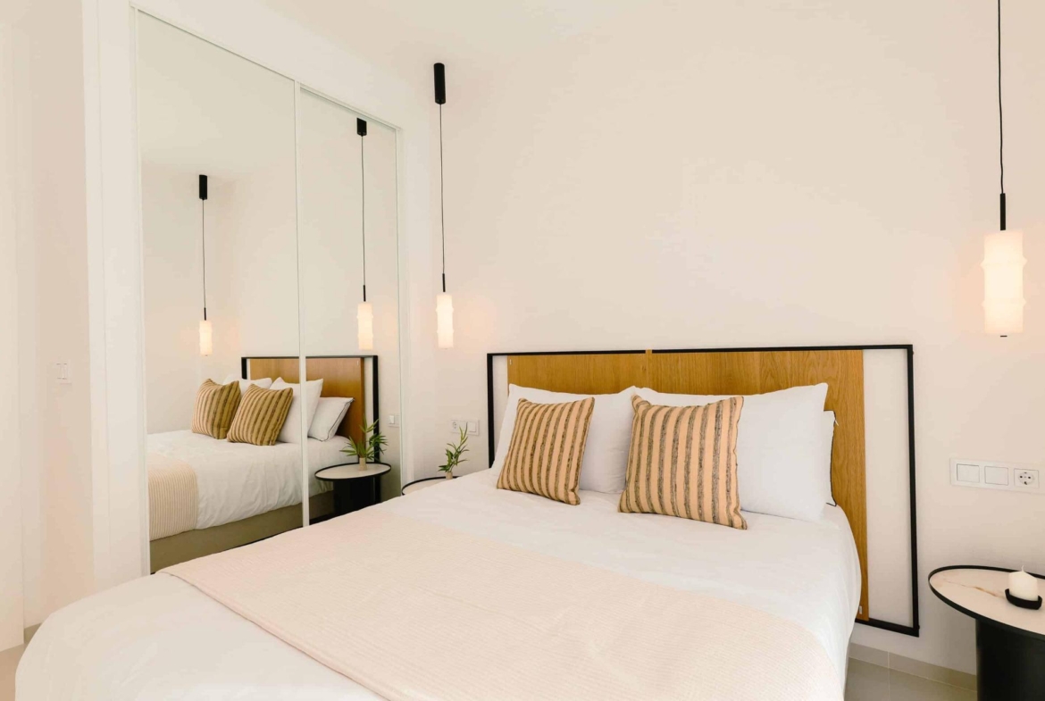 Bright modern bedroom with striped cushions and sleek mirrored wardrobe in 2-bedroom ground floor bungalow, Doña Pepa, Rojales.