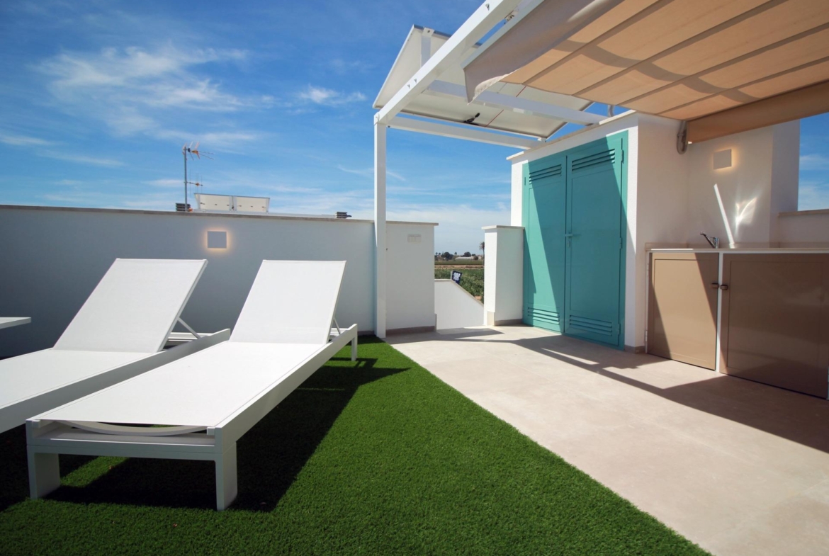 NEW-BUILD-RESIDENTIAL-COMPLEX-IN-TORRE-DE-LA-HORADADA-2 Sun-drenched top floor apartment solarium in Torre de la Horadada with sleek sun loungers and modern shaded outdoor kitchen area.