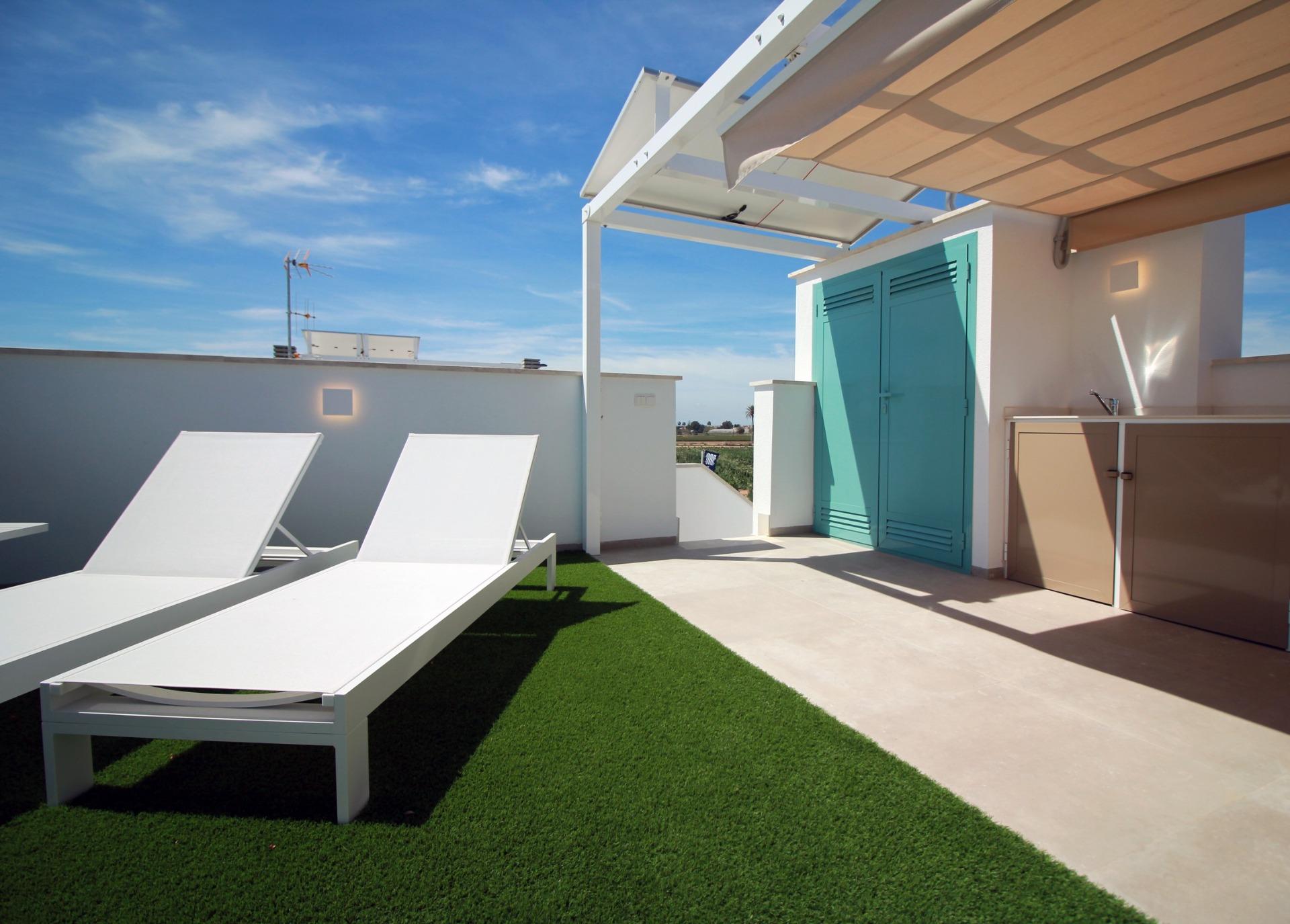 NEW-BUILD-RESIDENTIAL-COMPLEX-IN-TORRE-DE-LA-HORADADA-2 Sun-drenched top floor apartment solarium in Torre de la Horadada with sleek sun loungers and modern shaded outdoor kitchen area.