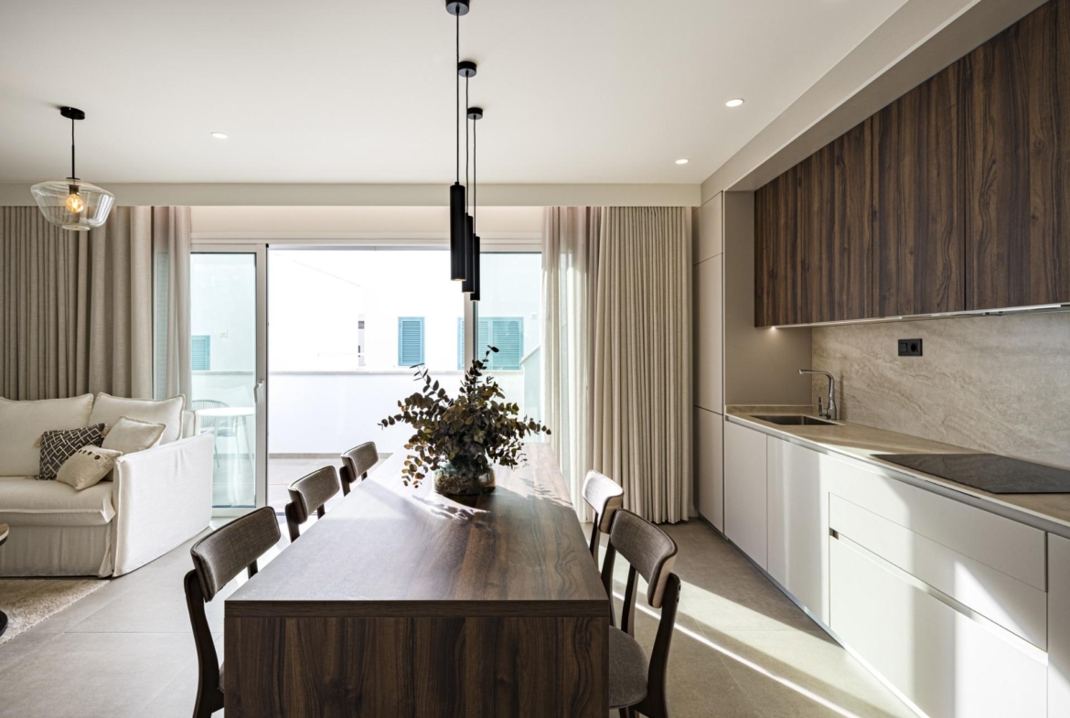 NEW-BUILD-RESIDENTIAL-COMPLEX-IN-TORRE-DE-LA-HORADADA-27 Modern sunlit kitchen and dining area with elegant wood accents in luxury 3-bedroom top floor apartment in Torre de la Horadada.