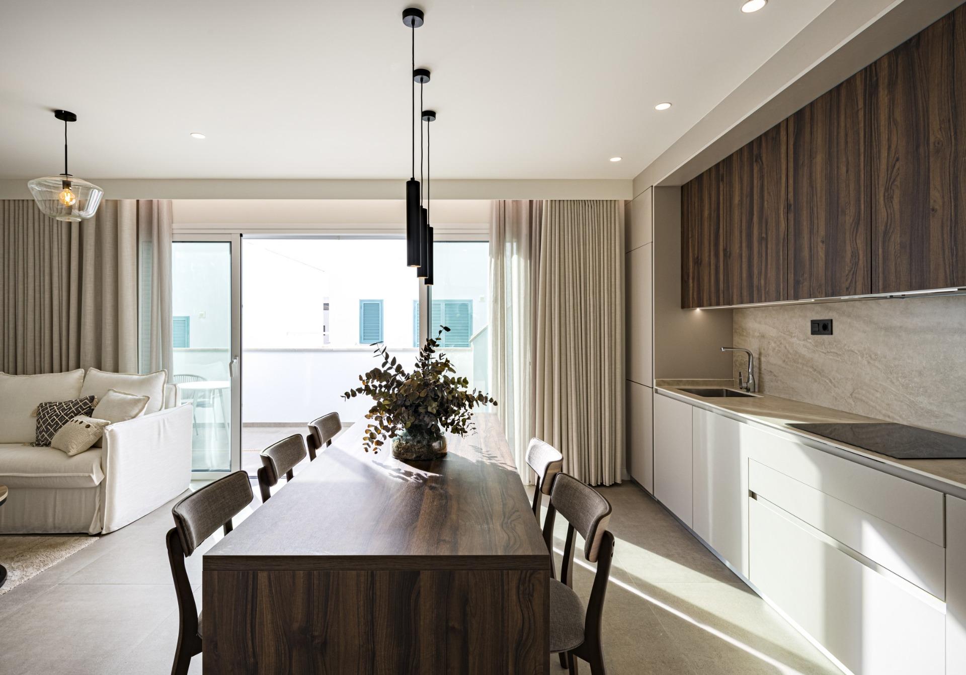 NEW-BUILD-RESIDENTIAL-COMPLEX-IN-TORRE-DE-LA-HORADADA-27 Modern sunlit kitchen and dining area with elegant wood accents in luxury 3-bedroom top floor apartment in Torre de la Horadada.
