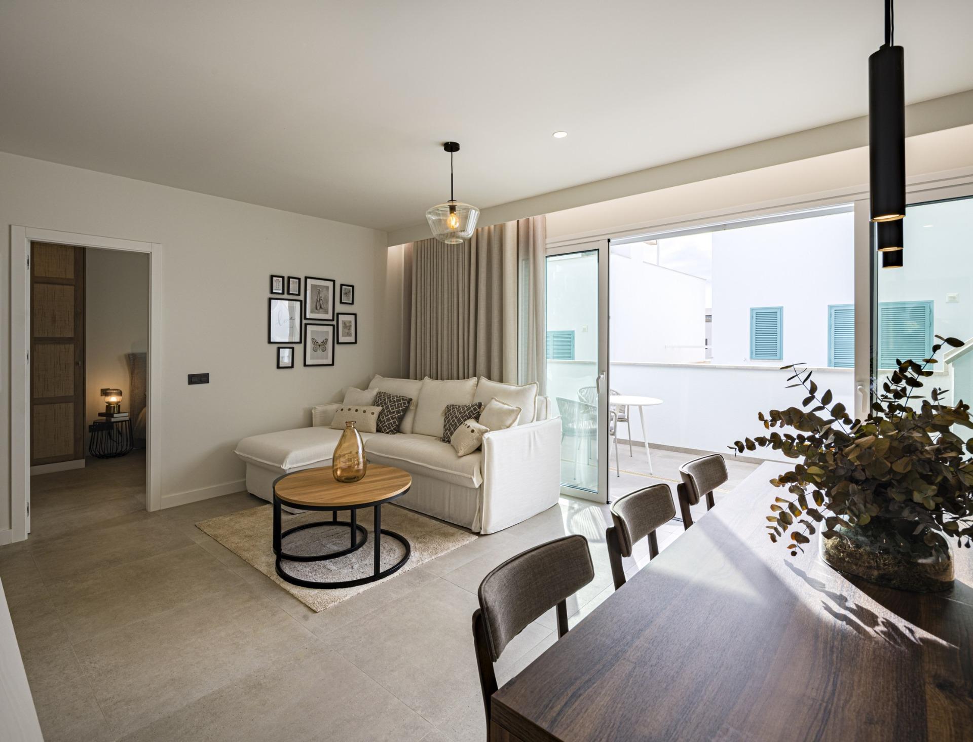 NEW-BUILD-RESIDENTIAL-COMPLEX-IN-TORRE-DE-LA-HORADADA-28 Bright modern living room with elegant sofa and dining area opening onto private terrace in Torre de la Horadada top floor apartment