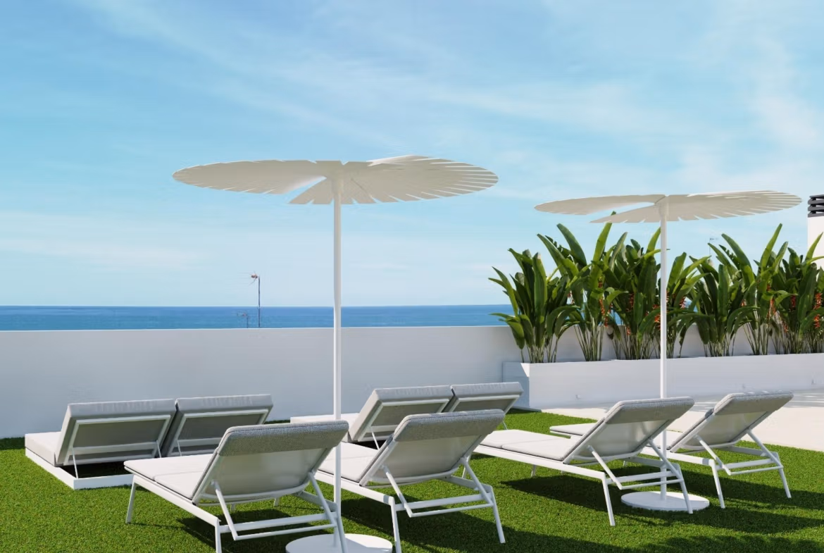 NEW-BUILD-RESIDENTIAL-IN-GUARDAMAR-DEL-SEGURA-14 Sun-drenched terrace with modern loungers and parasols overlooking the sparkling sea at a luxury 2-bedroom apartment in Guardamar del Segura.
