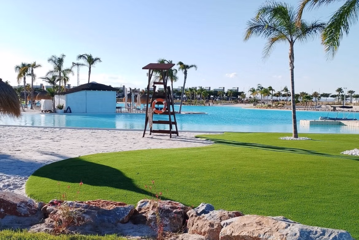 Sun-drenched pool area with lush landscaping and palm trees at Santa Rosalía Lake and Life Resort penthouse complex