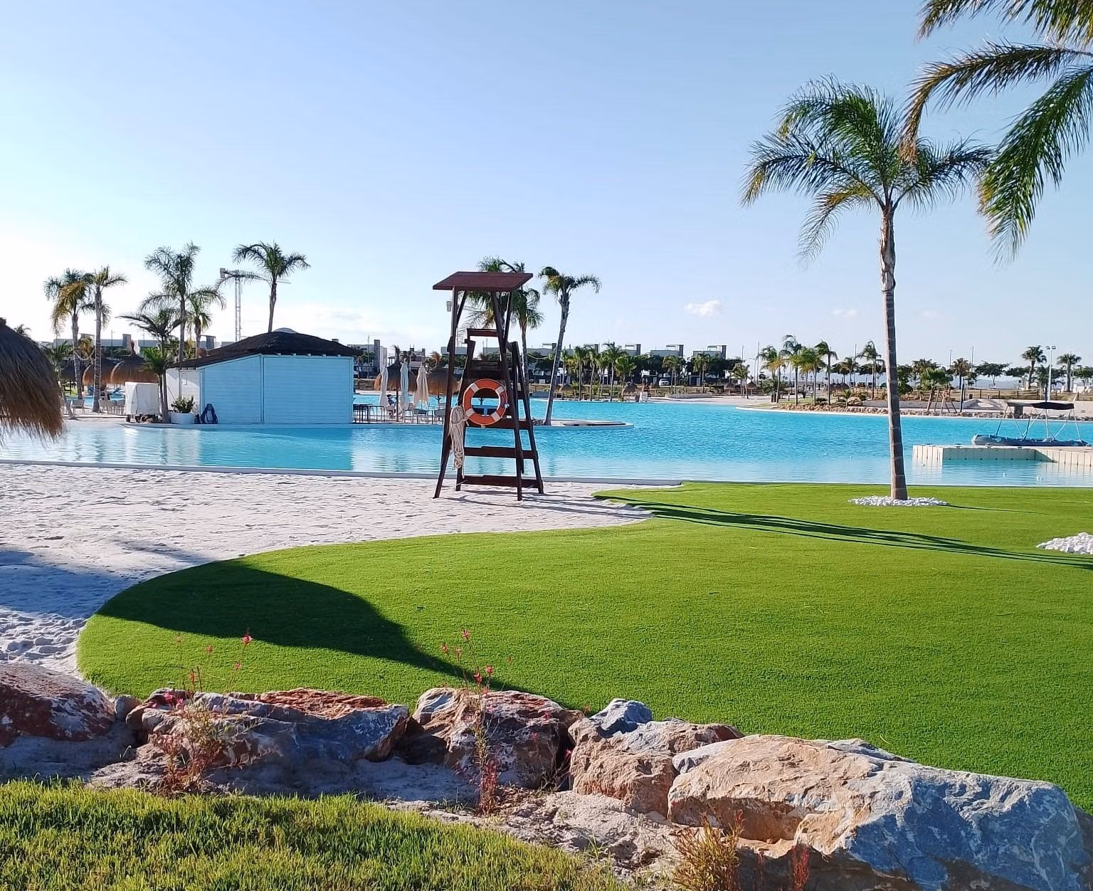 NEW-BUILD-RESIDENTIAL-IN-PRIVATE-GATED-RESORT-IN-PROVINCE-OF-MURCIA-16 Sun-drenched pool area with lush landscaping and palm trees at Santa Rosalía Lake and Life Resort penthouse complex