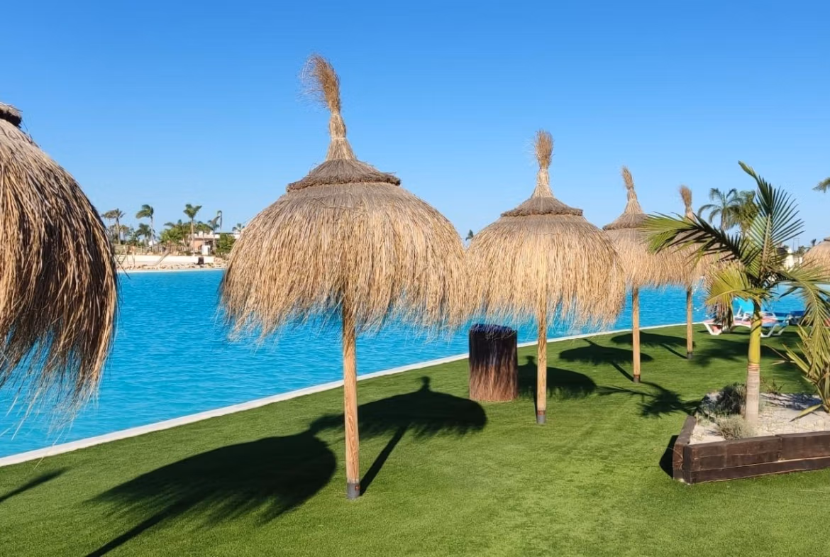 Sun-drenched private solarium with lush landscaping and thatched umbrellas at 3-bedroom penthouse in Santa Rosalía Lake and Life Resort