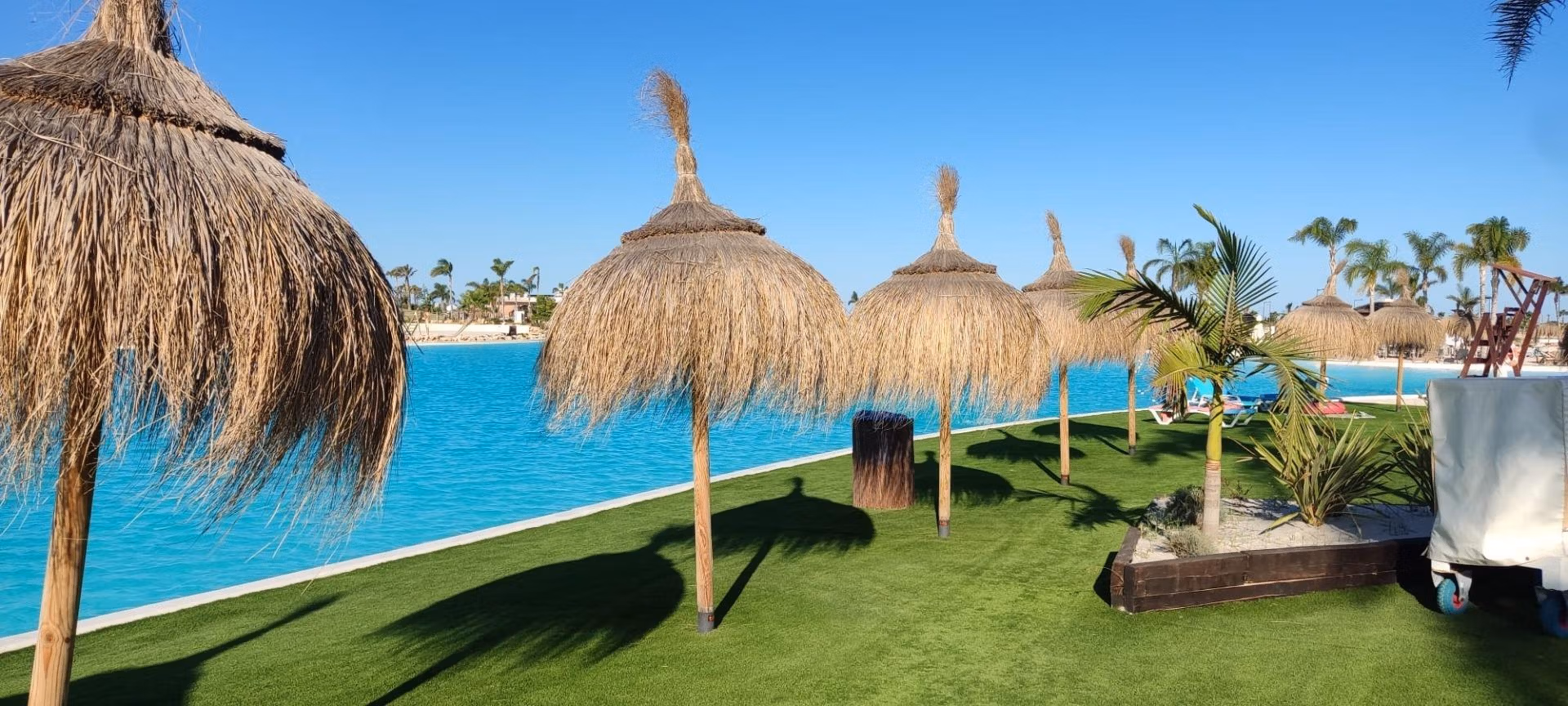 NEW-BUILD-RESIDENTIAL-IN-PRIVATE-GATED-RESORT-IN-PROVINCE-OF-MURCIA-17 Sun-drenched private solarium with lush landscaping and thatched umbrellas at 3-bedroom penthouse in Santa Rosalía Lake and Life Resort