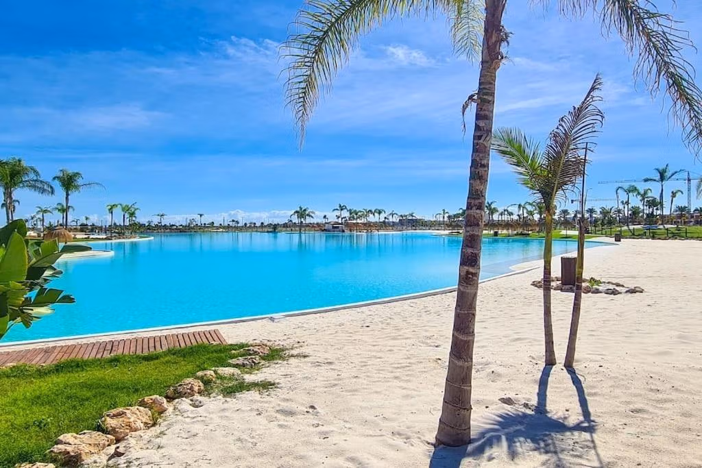 Sun-drenched private lagoon with pristine sandy beach and palm trees at Santa Rosalía Lake and Life Resort penthouse complex