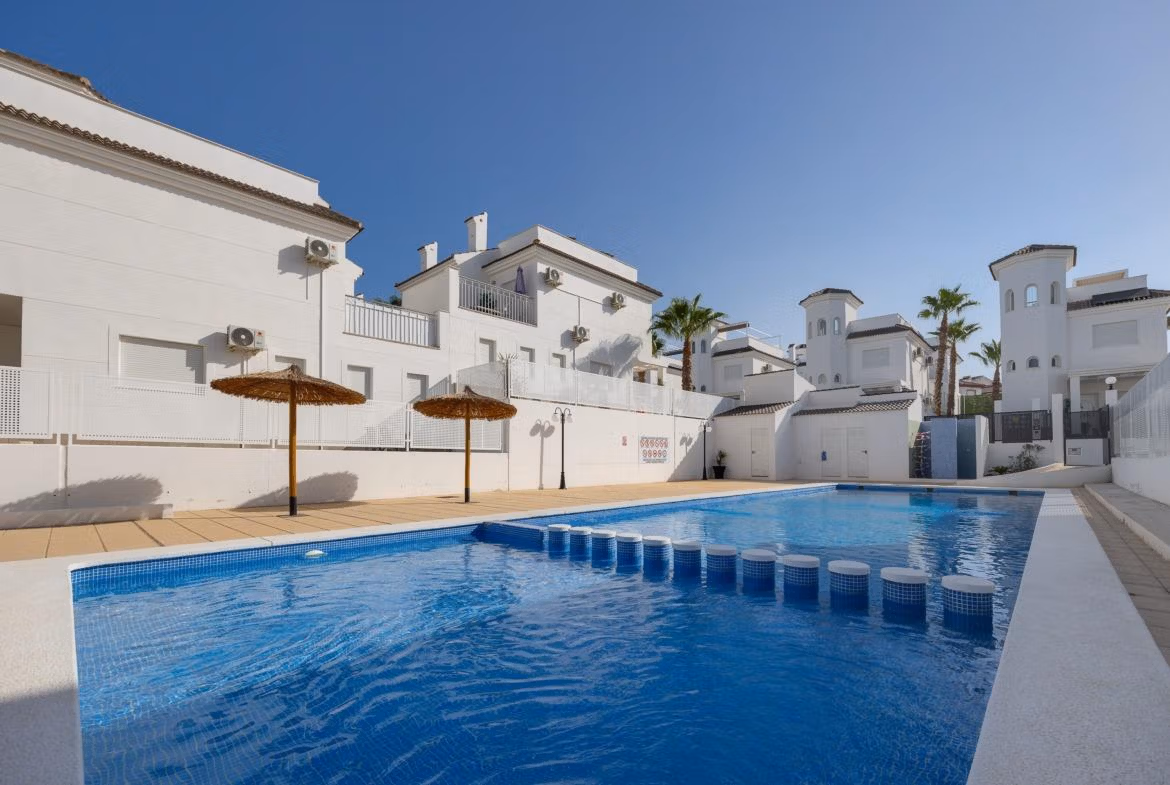 Bright, modern 3-bedroom villa in El Oasis, San Fulgencio featuring a private sparkling pool and sun-drenched terrace with umbrellas.