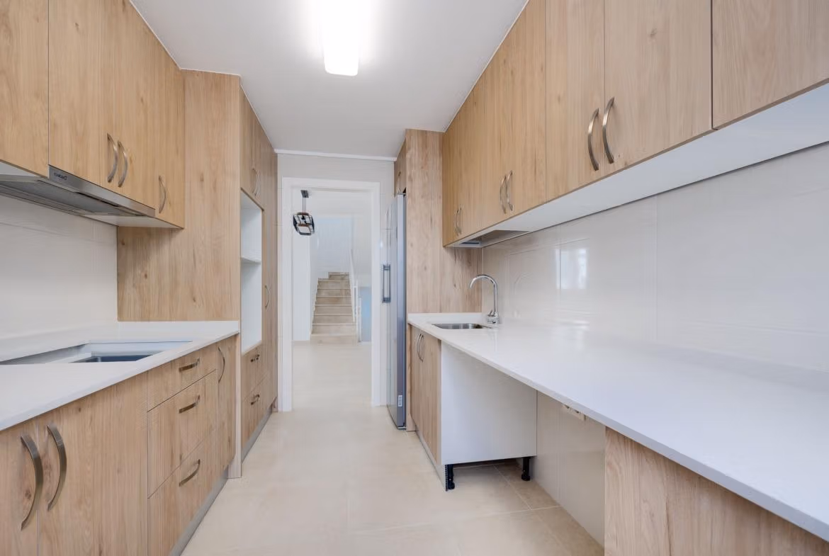 NEW-BUILD-RESIDENTIAL-IN-SAN-FULGENCIO-13 Modern, bright kitchen with sleek wooden cabinetry and white countertops in a 2 bedroom semi-detached villa at El Oasis La Marina Urbanisation